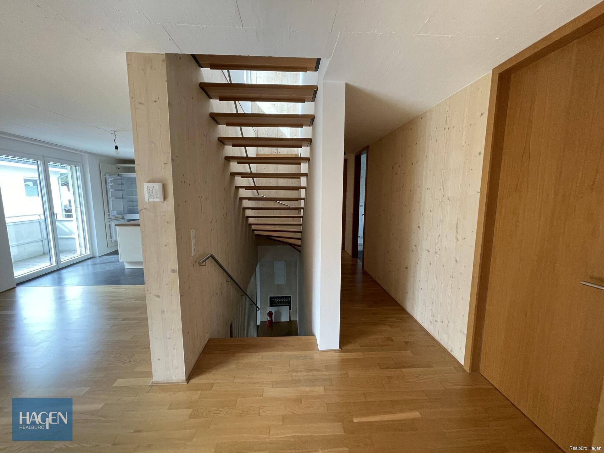 Moderner Flur mit Holztreppe und Holzwänden, der zu weiteren Räumen führt.