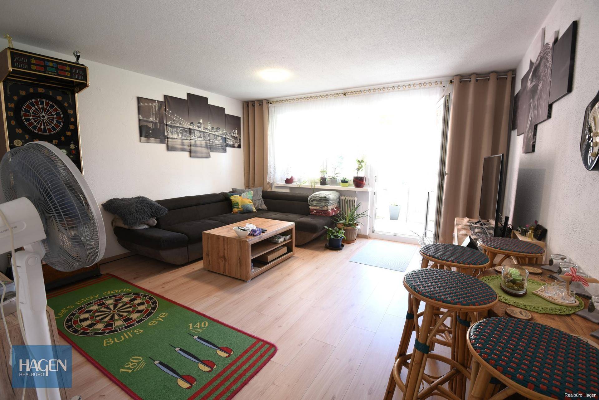 Gemütliches Wohnzimmer mit Sofa, Couchtisch und Zugang zum sonnigen Außenbereich.