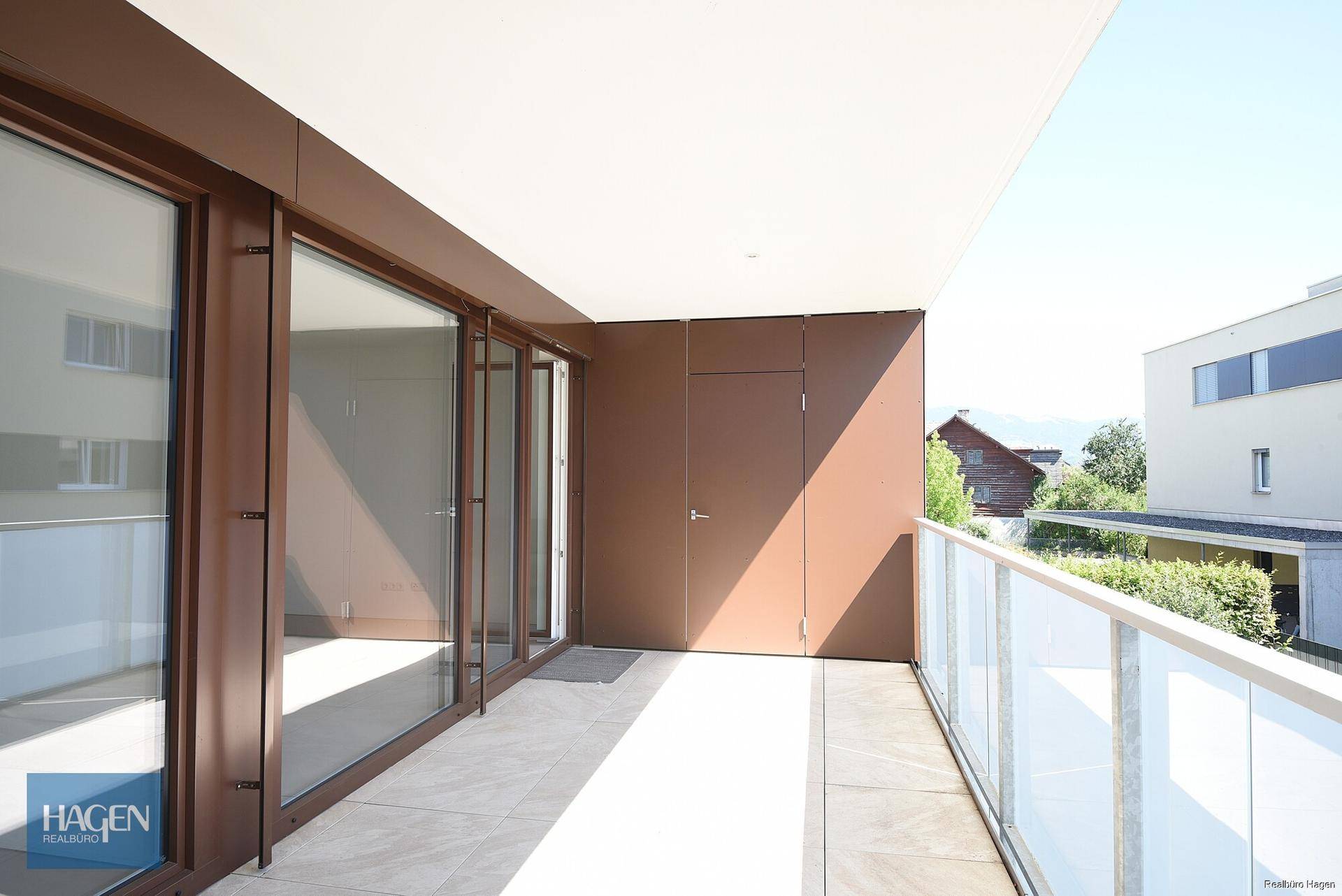 Geräumiger Balkon mit Glasgeländer und Zugang zu den Innenräumen, ideal für Entspannung im Freien.