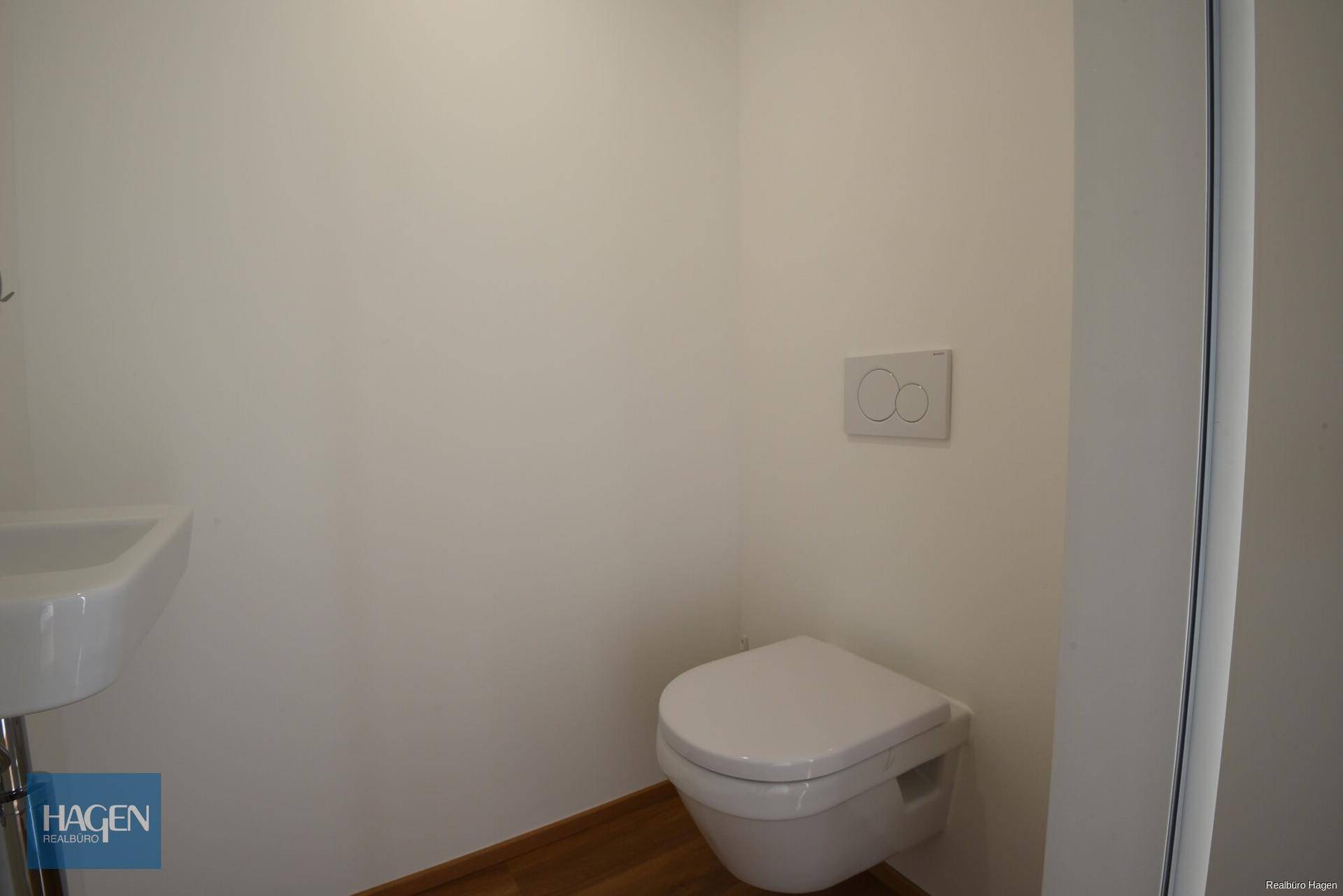 Modernes Gäste-WC mit wandhängender Toilette und kleinem Eckwaschbecken.