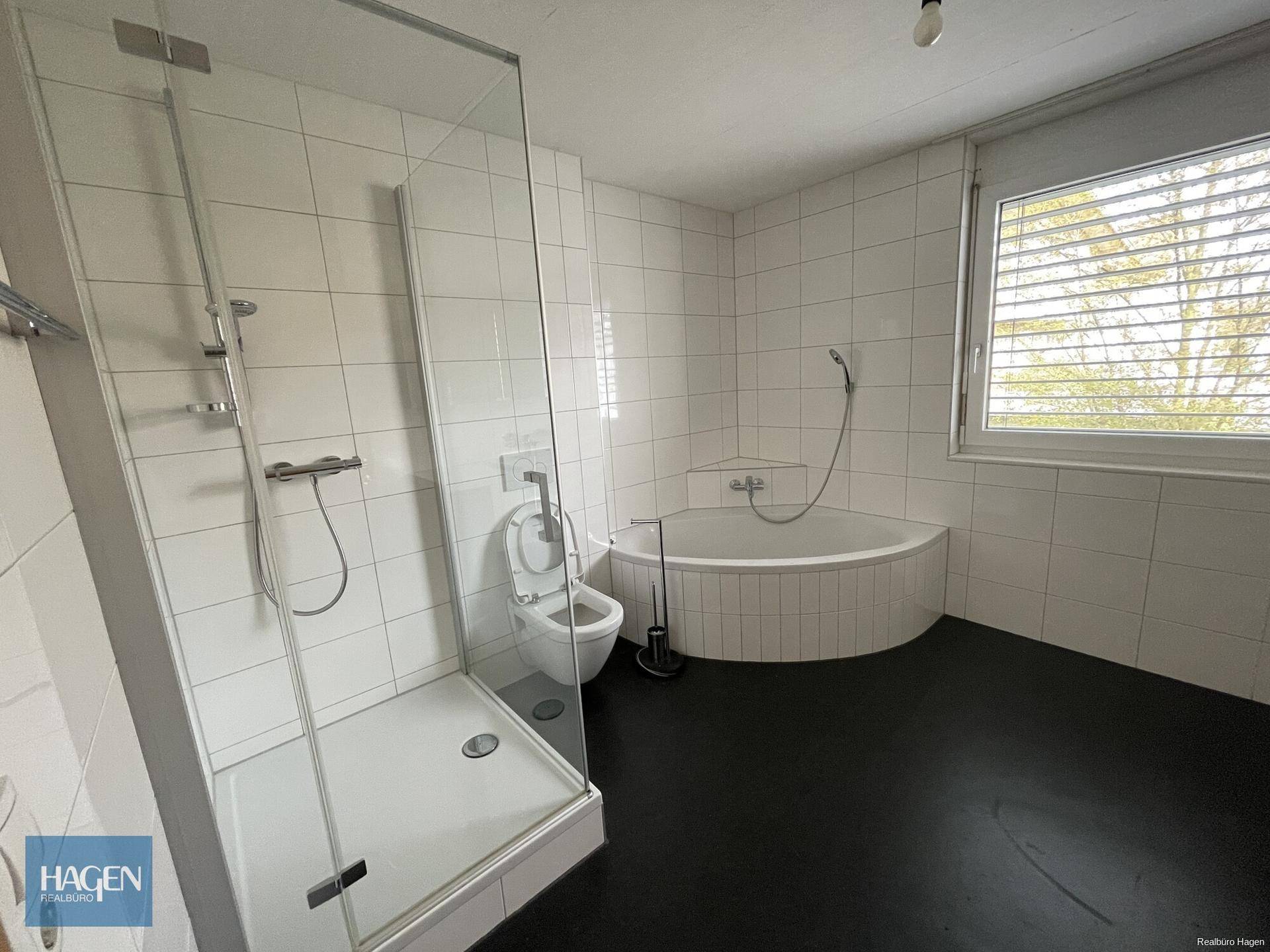 Geräumiges Badezimmer mit Dusche, Eckbadewanne und Fenster für natürliche Belüftung.