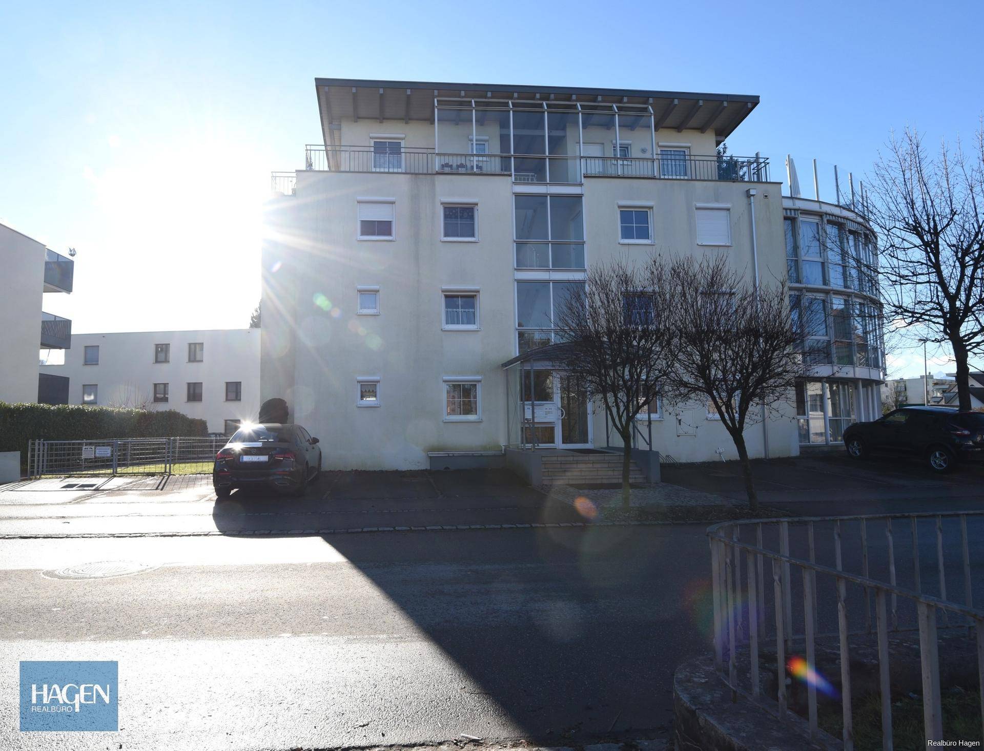 Moderne Wohnanlage mit heller Fassade, großen Fenstern und Balkonen unter blauem Himmel.