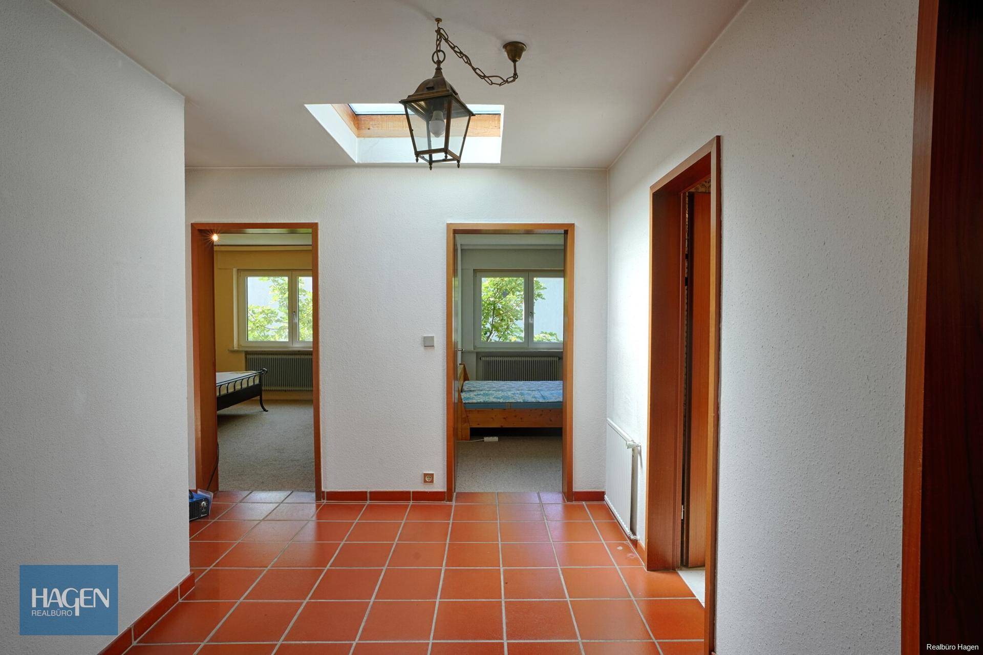 Heller Flur mit Terrakotta-Fliesenboden und Zugang zu mehreren Zimmern.