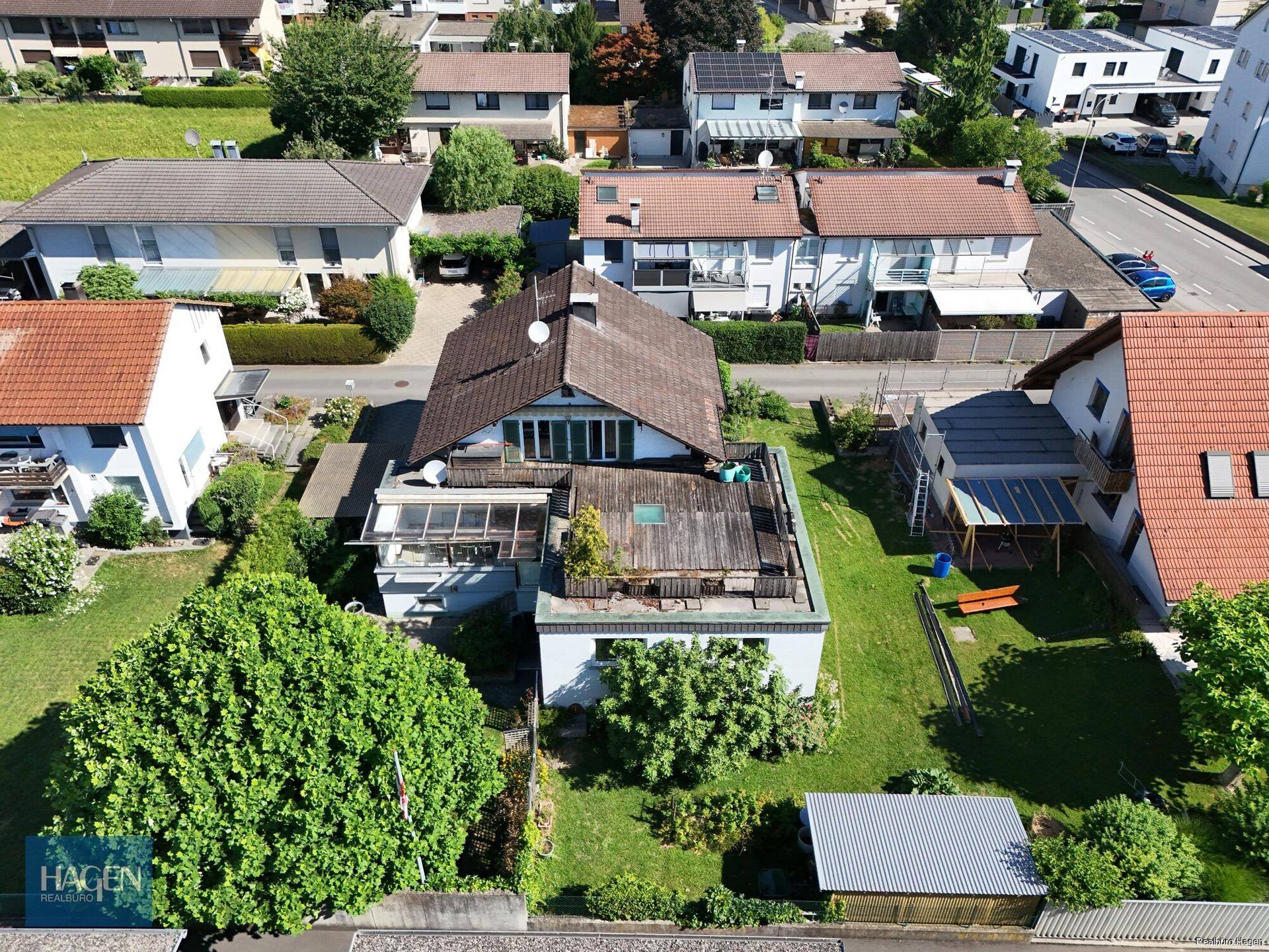 Luftaufnahme des Hauses mit Dachterrasse, Garten und umliegender Wohnbebauung.