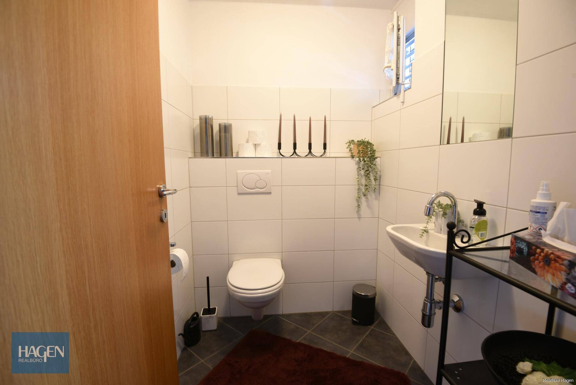 Gäste-WC mit Waschbecken, Toilette und Fliesenboden.