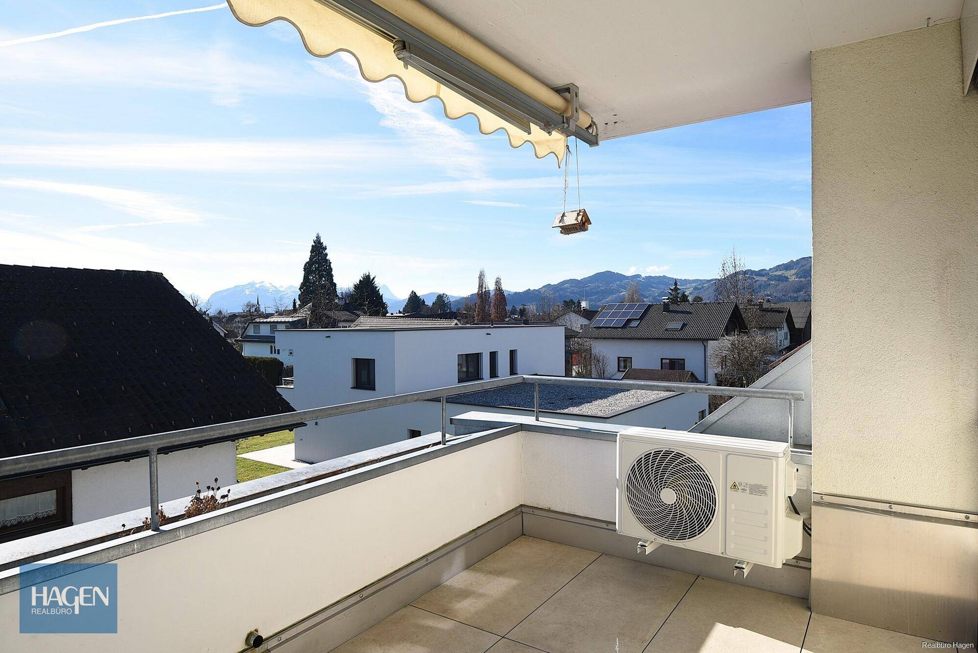 Geräumiger Balkon mit Markise, Klimaanlage und weitem Blick auf die umliegende Berglandschaft.
