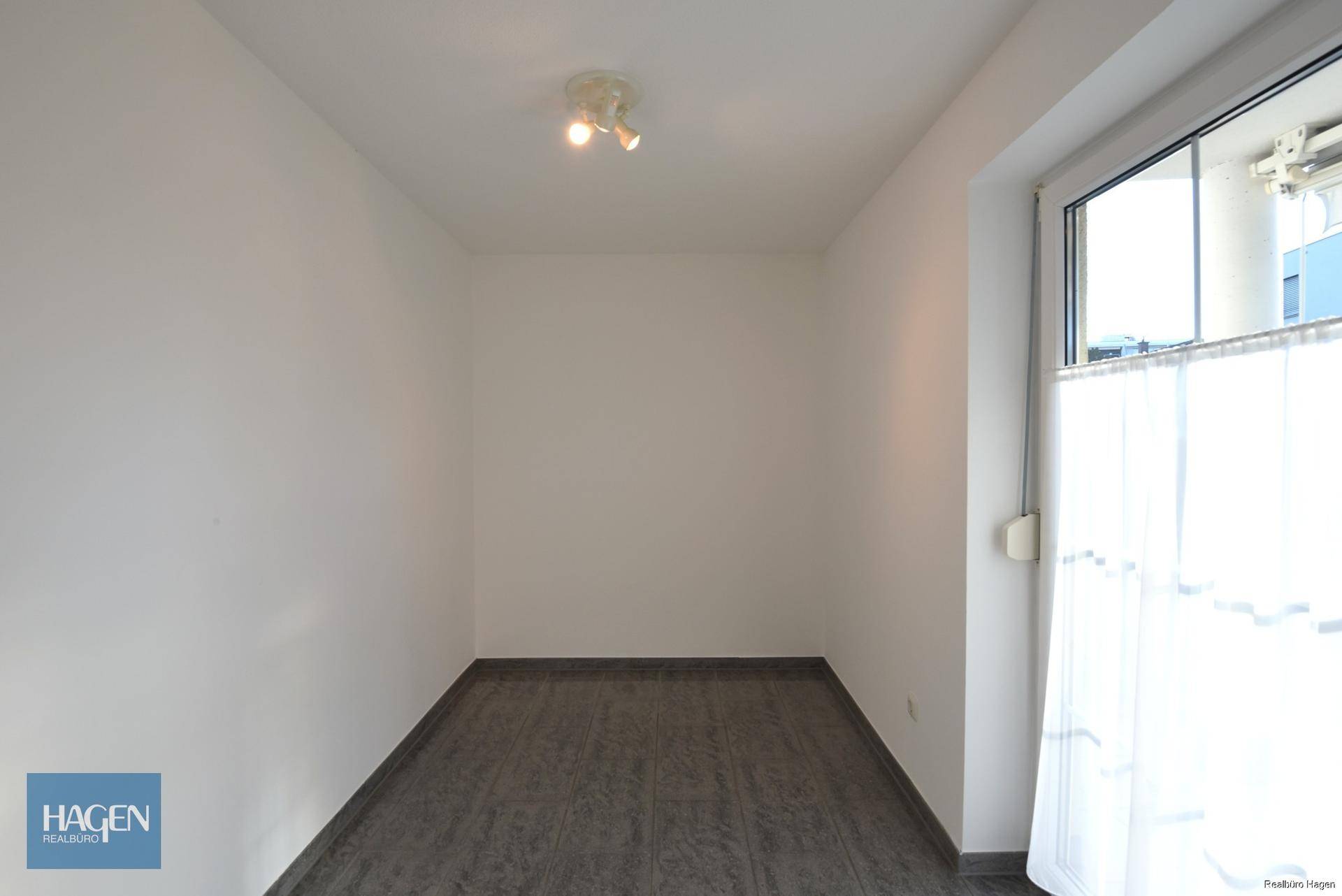 Kleiner, heller Raum mit Fliesenboden und Fenster, vielseitig nutzbar als Büro oder Abstellraum.