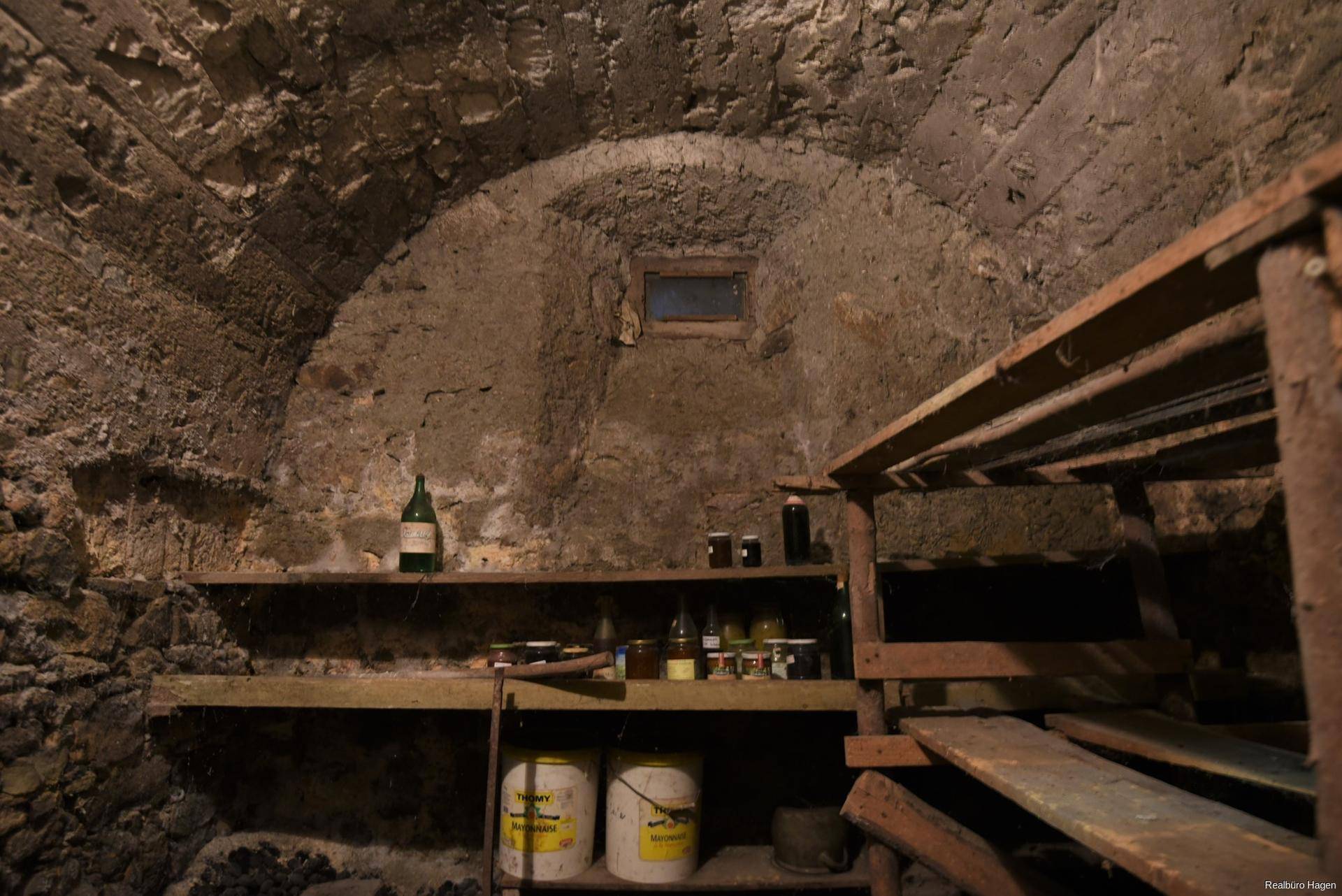 Historischer Gewölbekeller mit Steinmauern und Holzregalen, ideal zur Lagerung.