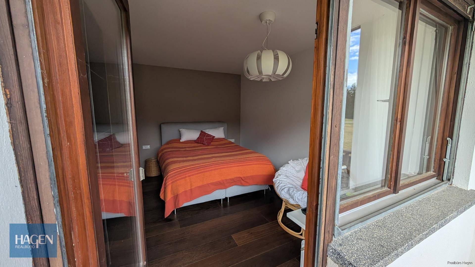 Gemütliches Schlafzimmer mit Holzboden, Doppelbett und Zugang zu einem Außenbereich.