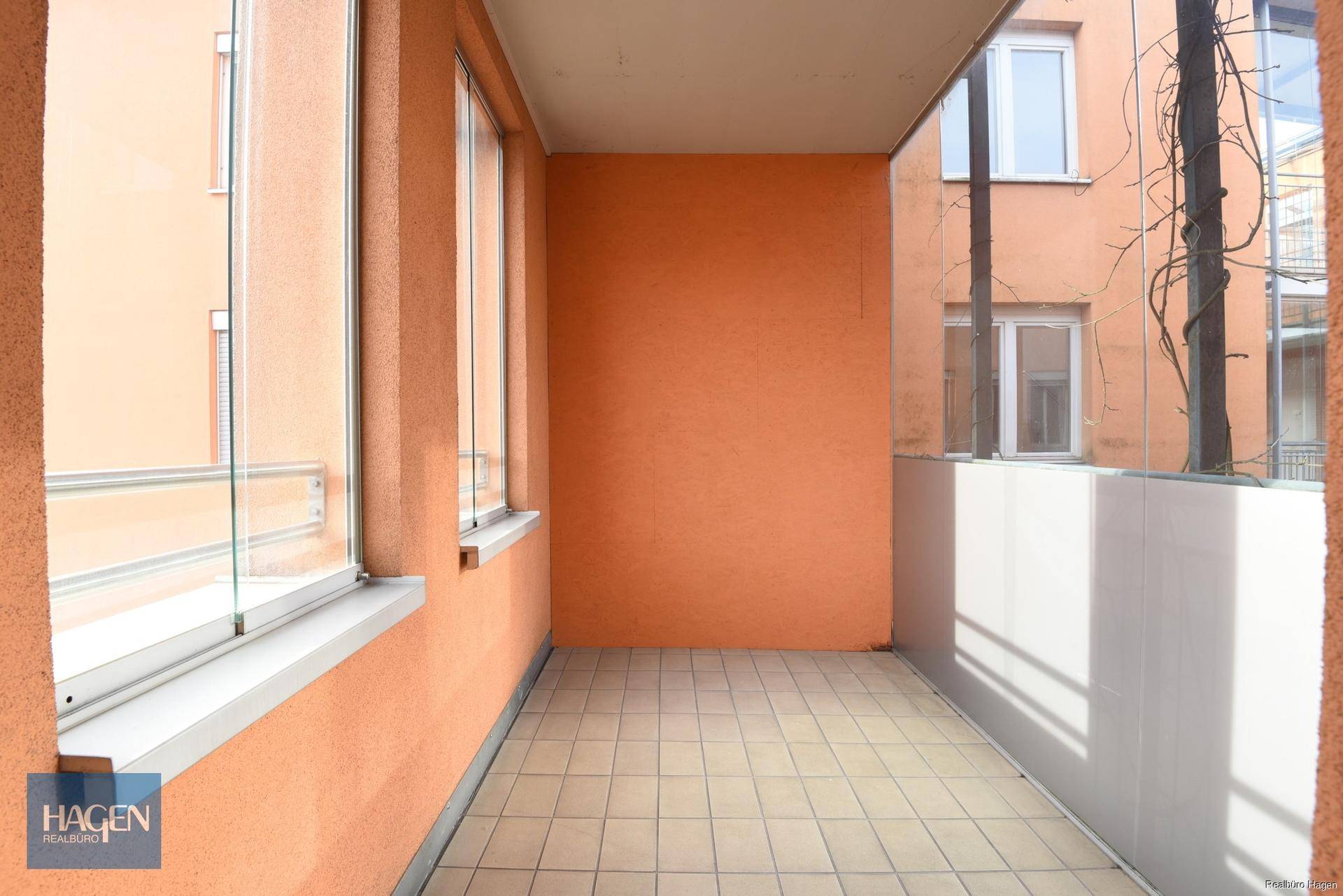 Heller Balkon mit Fliesenboden und Glasbrüstung, ideal für entspannte Stunden im Freien.