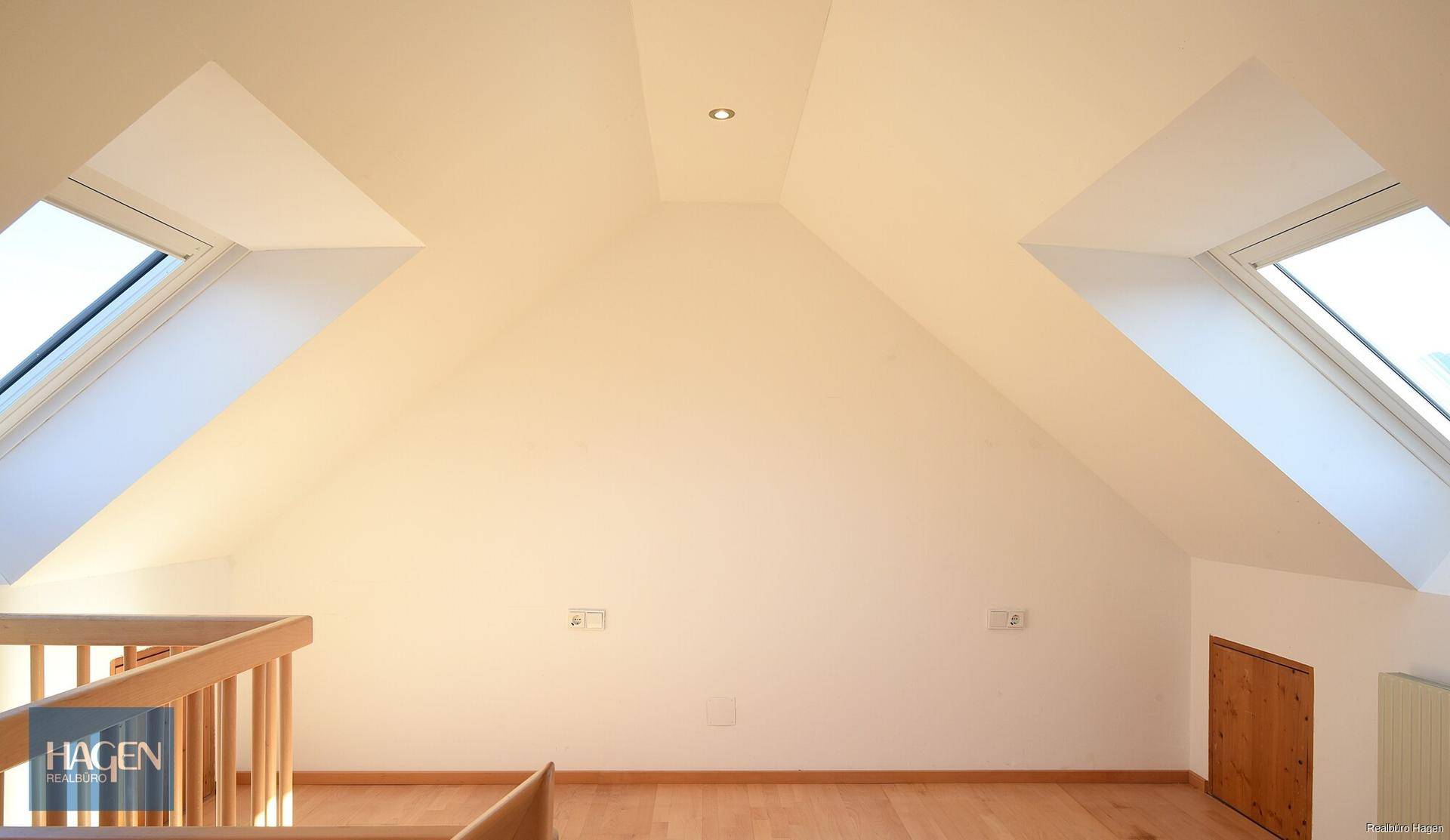 Heller Dachbodenraum mit schrägen Decken, Dachfenstern und Holzfußboden, ideal für Wohnzwecke.
