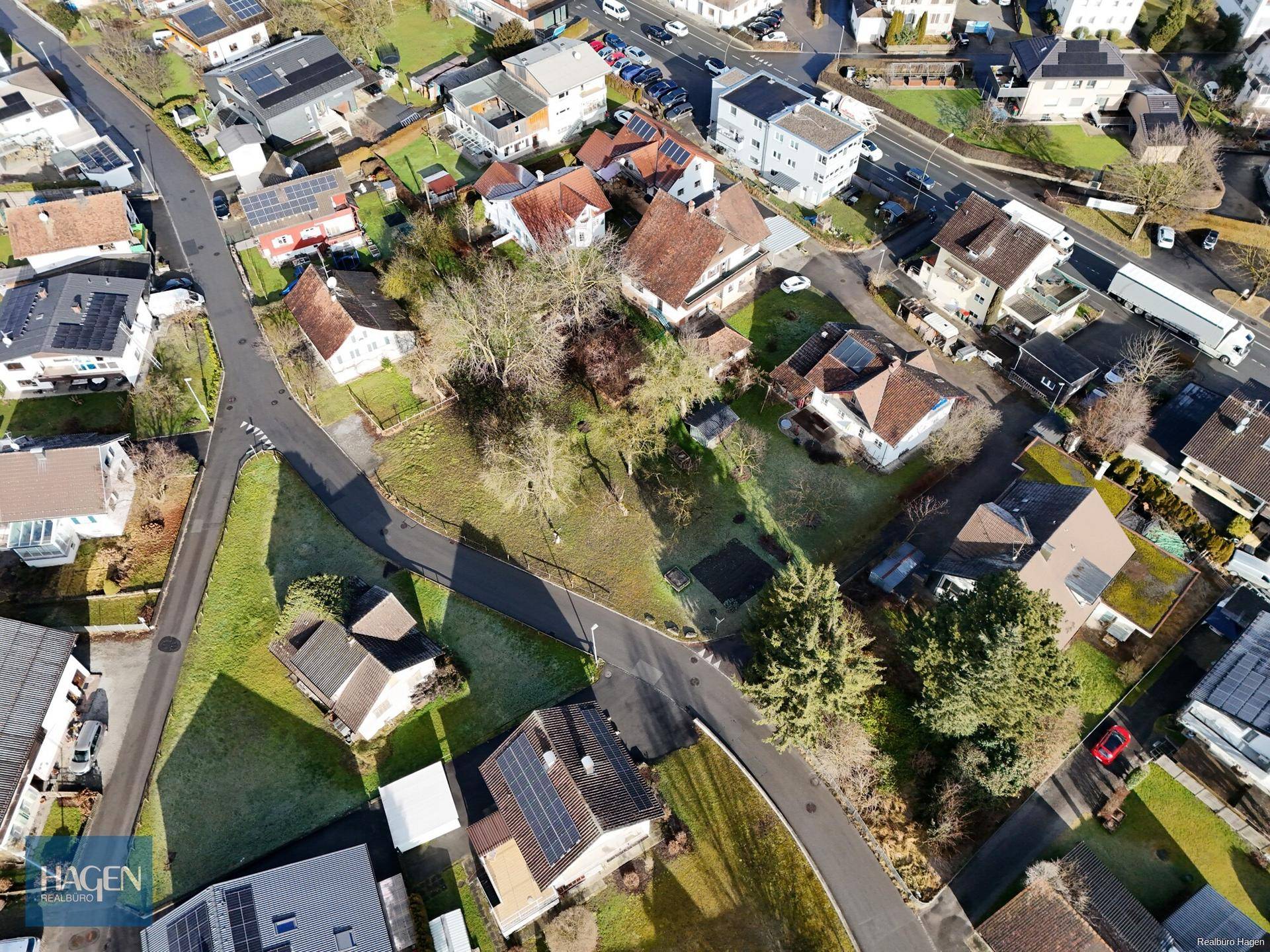 Überblick über eine Wohnsiedlung mit verschiedenen Häusern, Straßen und Grünflächen unter blauem Himmel.