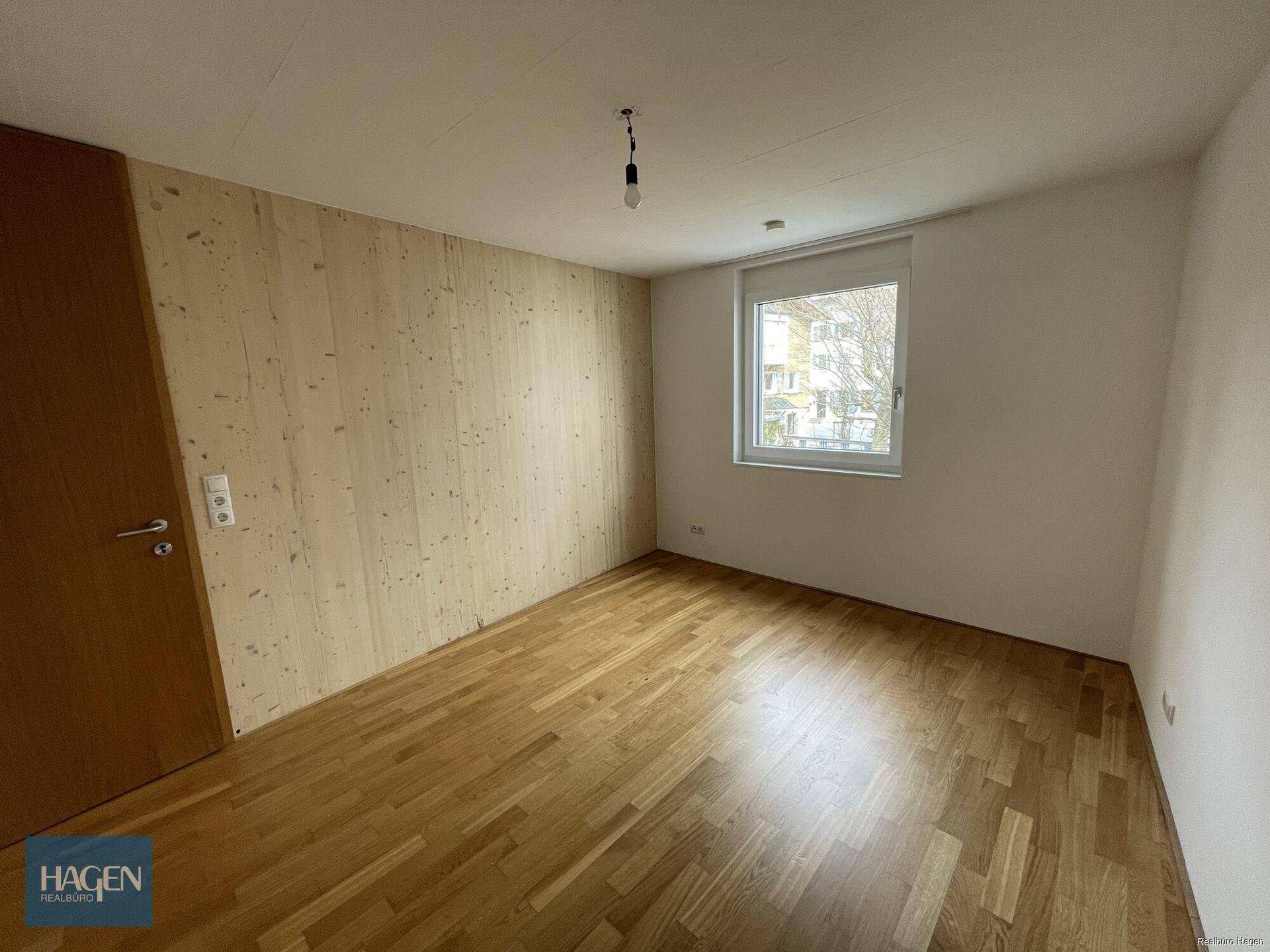 Schlafzimmer mit Holzboden und Fenster, das viel Tageslicht in den Raum lässt.