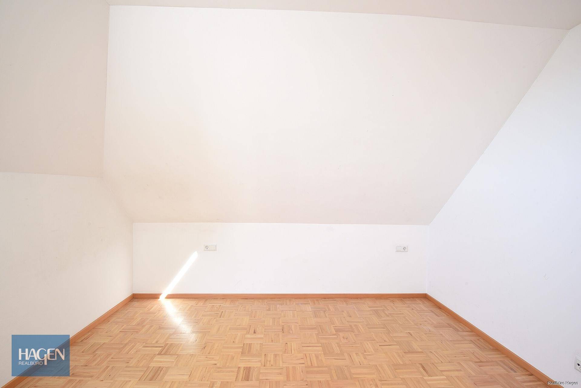 Heller Raum im Dachgeschoss mit Parkettboden und charakteristischer Dachschräge.