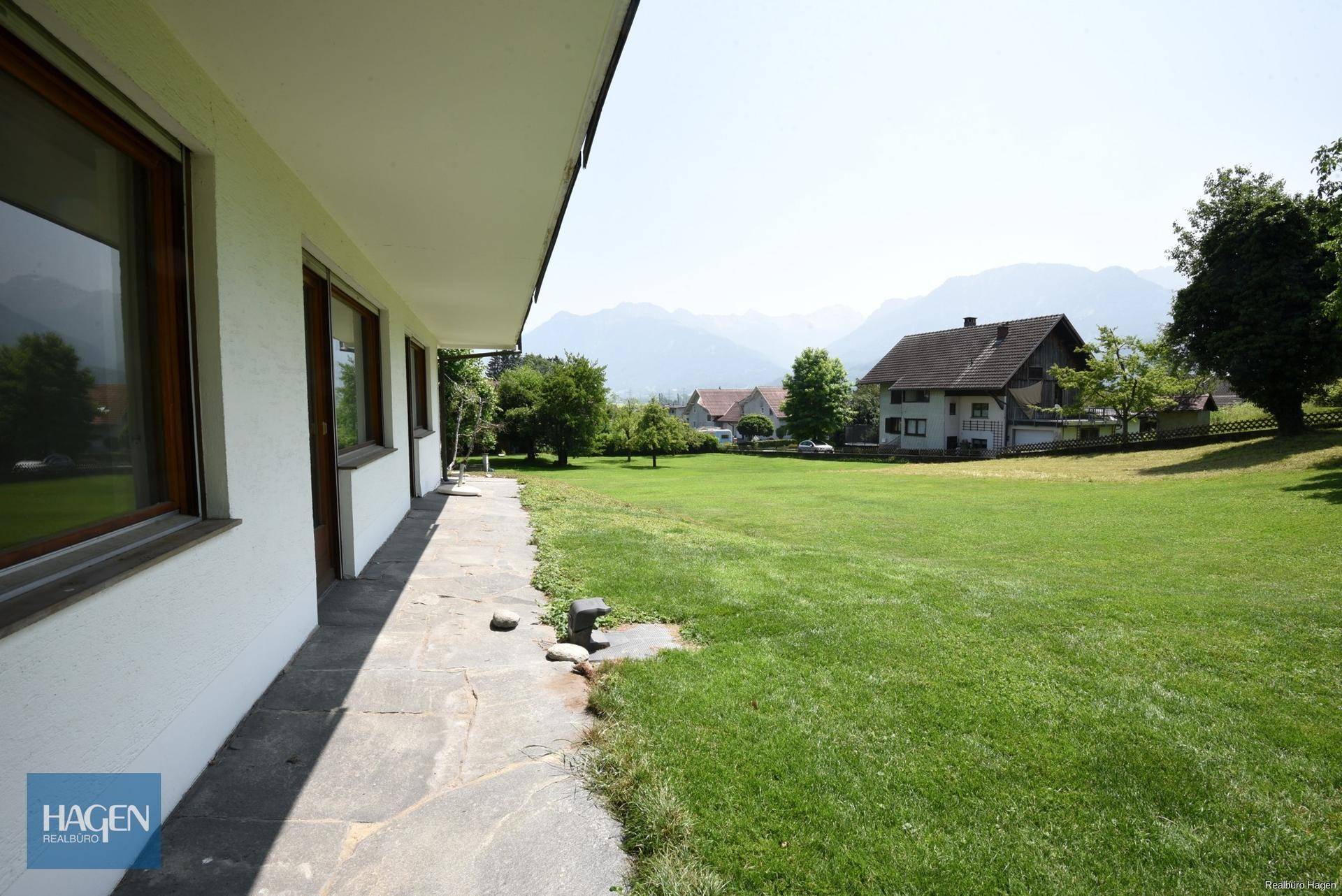 Seitlicher Zugang zum Haus mit Steinplattenweg und weitläufigem Garten.