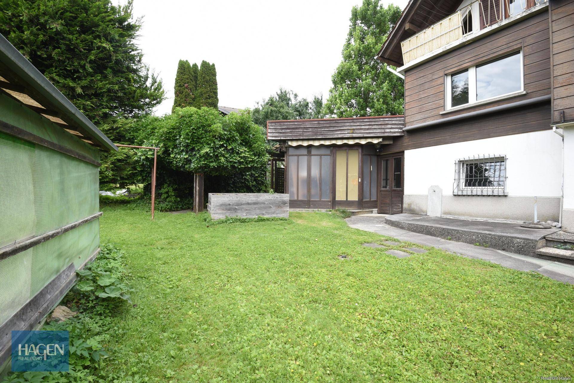 Großer Gartenbereich mit Rasenfläche, Bäumen und einem kleinen Schuppen.