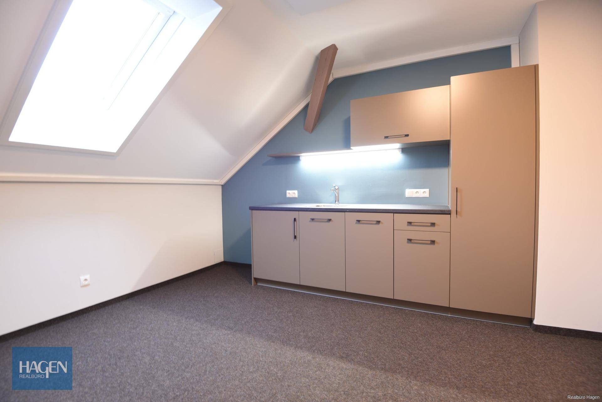 Dachgeschossraum mit Teeküche, Dachfenster und schrägen Wänden, ideal für eine kleine Arbeitsfläche.