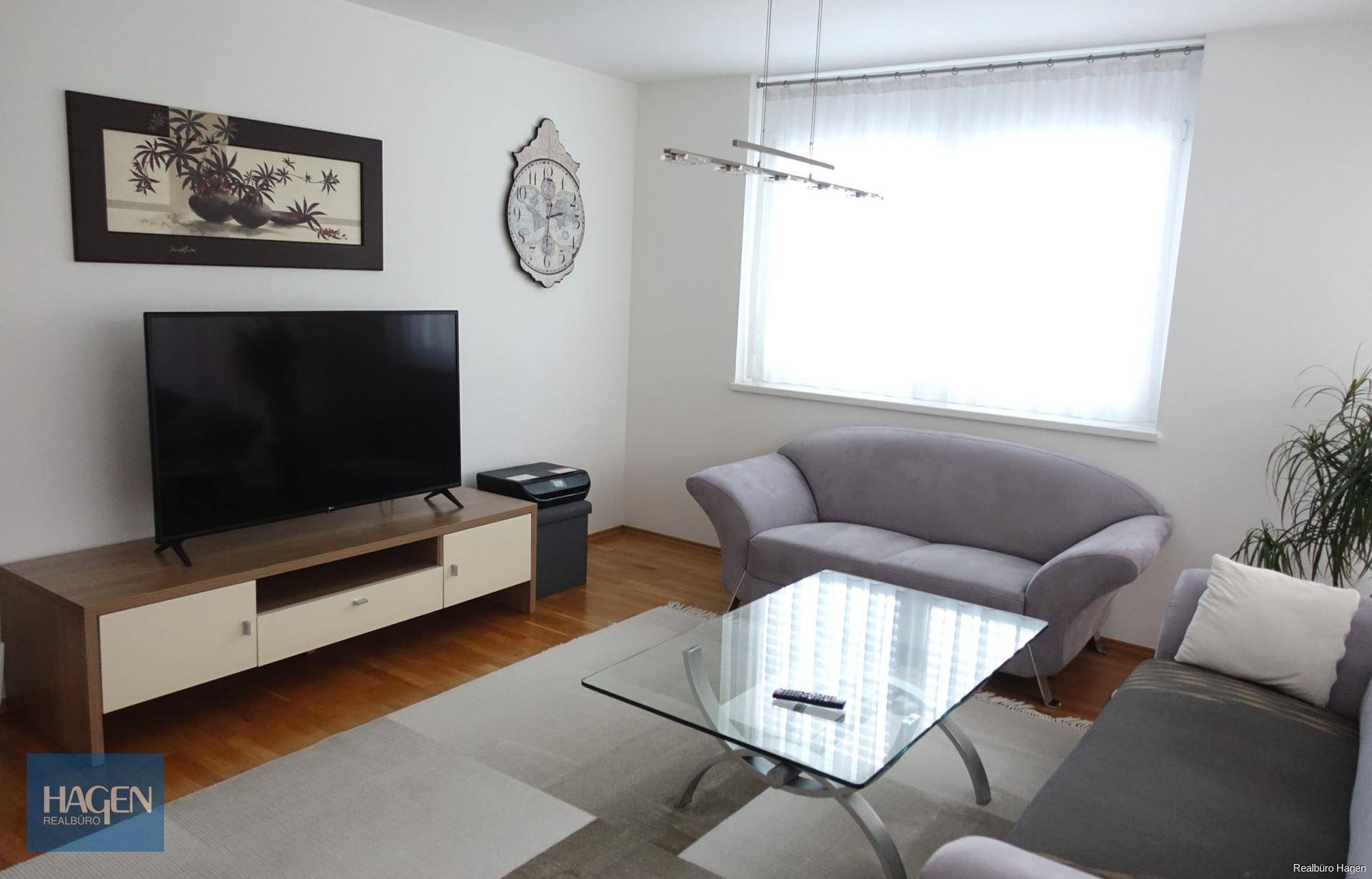 Helles Wohnzimmer mit Holzfußboden, bequemen Sofas und einem großen Fenster.