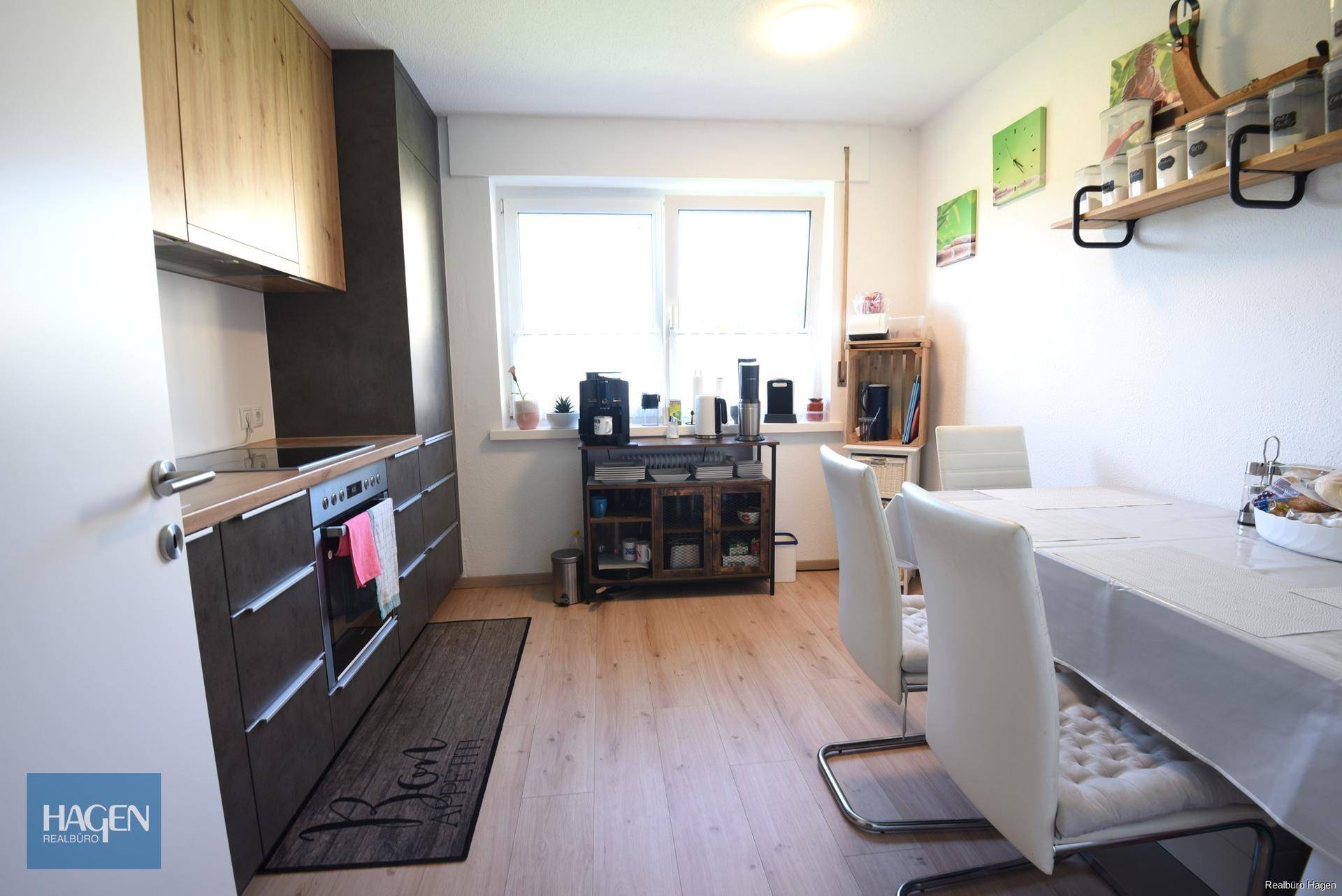 Moderne Küche mit Essbereich, hellen Holzschränken und Fenster für natürliches Licht.
