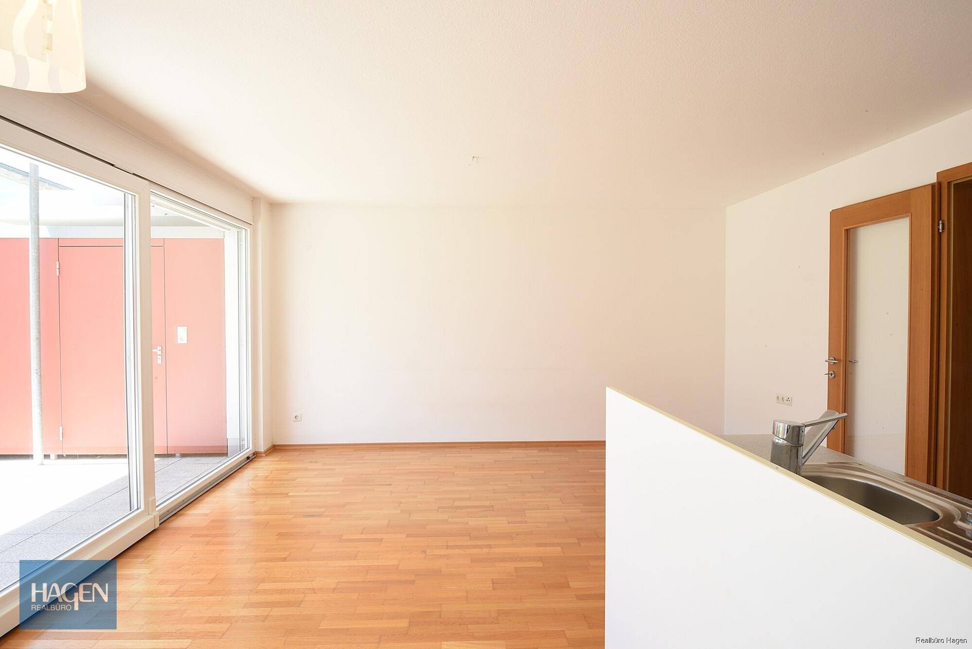 Lichtdurchfluteter Wohnbereich mit großen Schiebetüren und hellem Holzboden, ideal für offenes Wohnen.