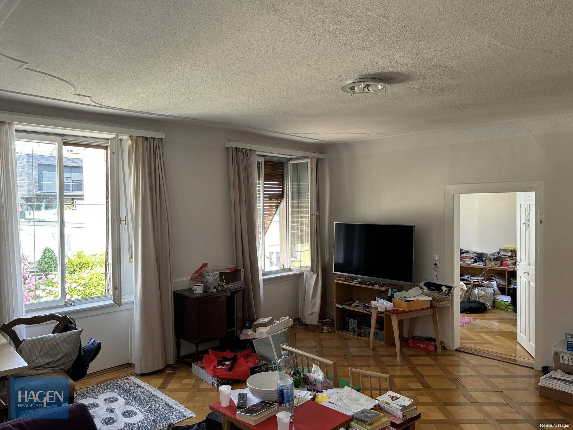 Helles Wohnzimmer mit Parkettboden, großen Fenstern und Blick ins Grüne.