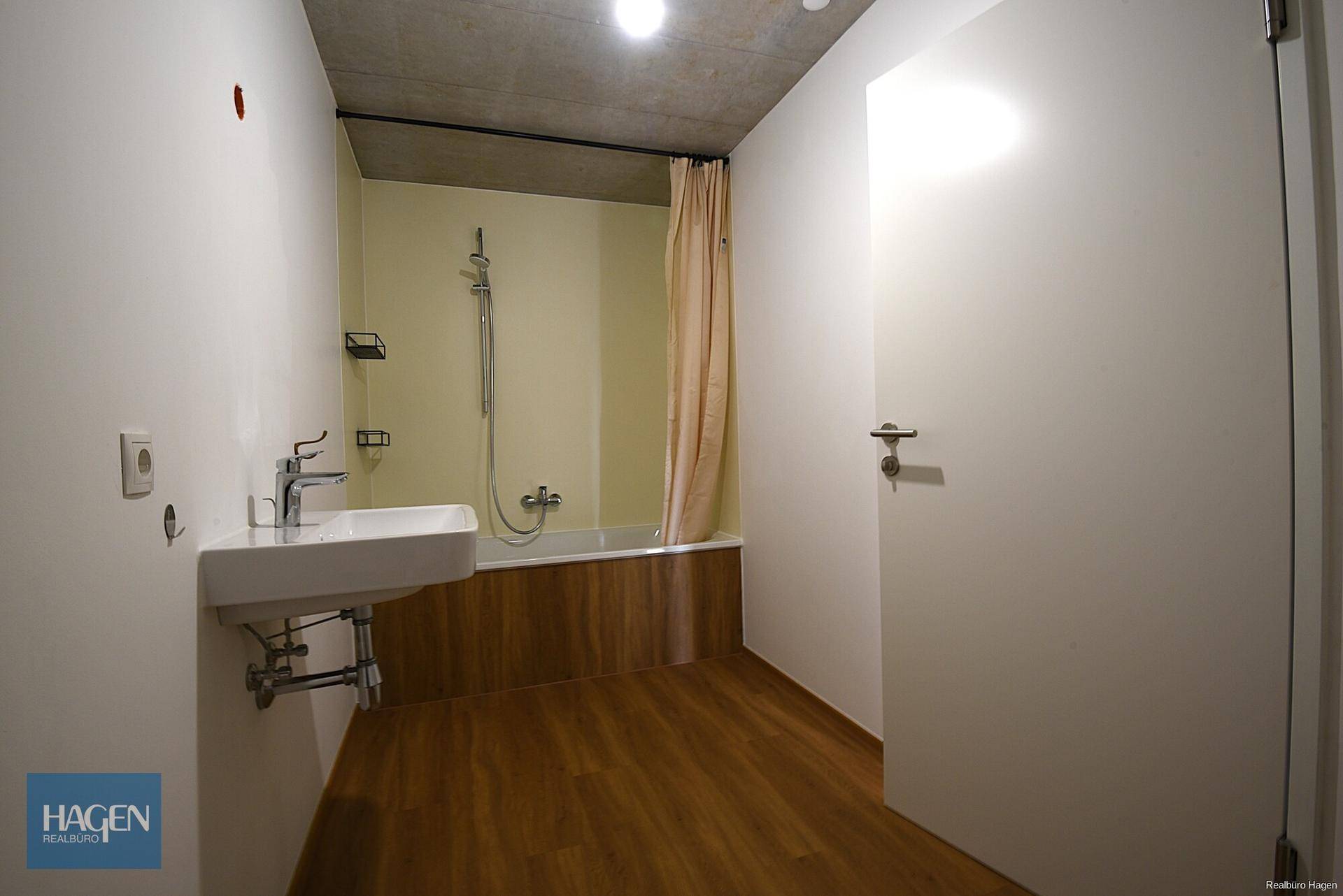Badezimmer mit Badewanne, Dusche und modernem Waschbecken, Holzakzente am Wannenrand.