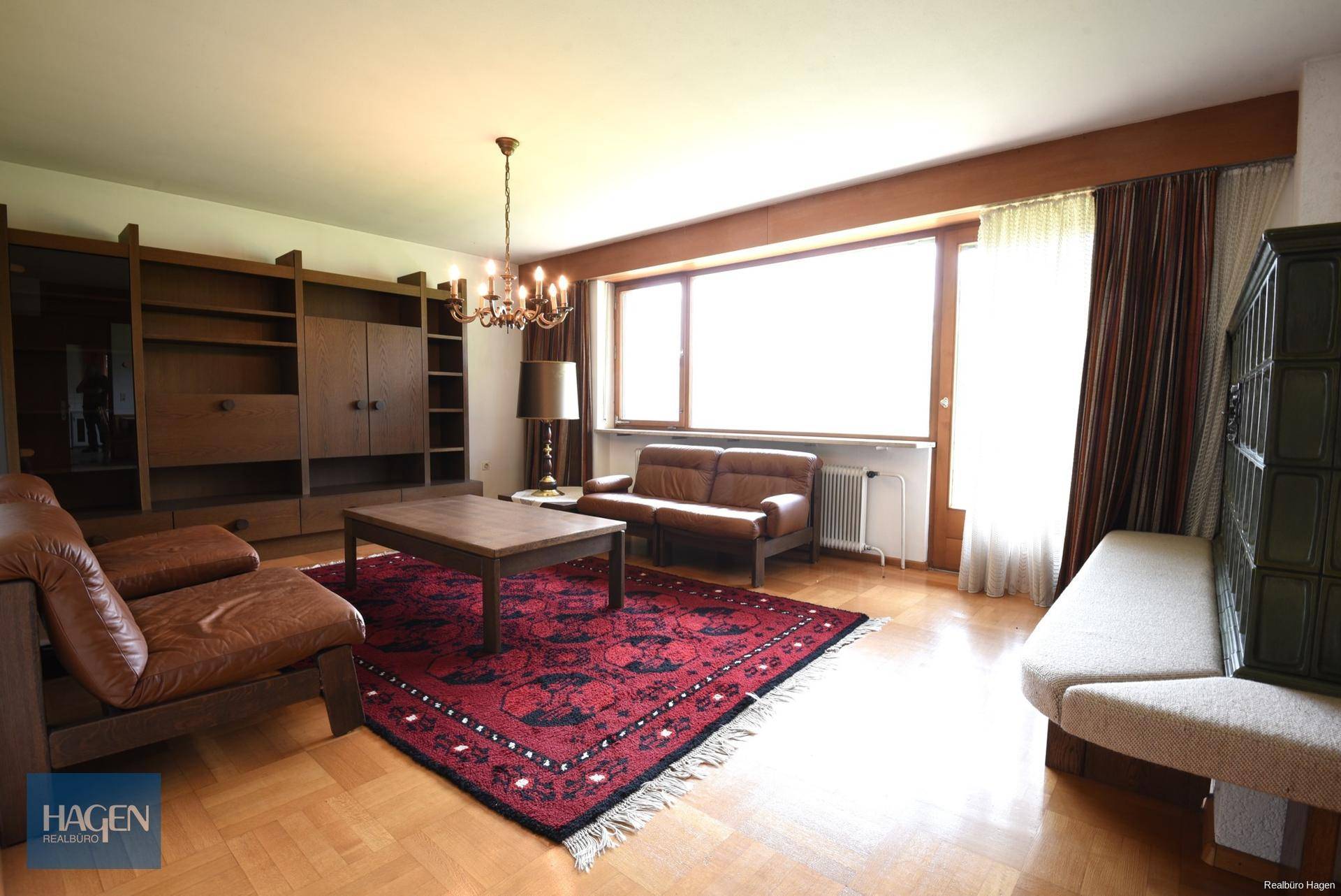 Geräumiges Wohnzimmer mit Holzboden, großem Fenster und traditioneller Einrichtung.