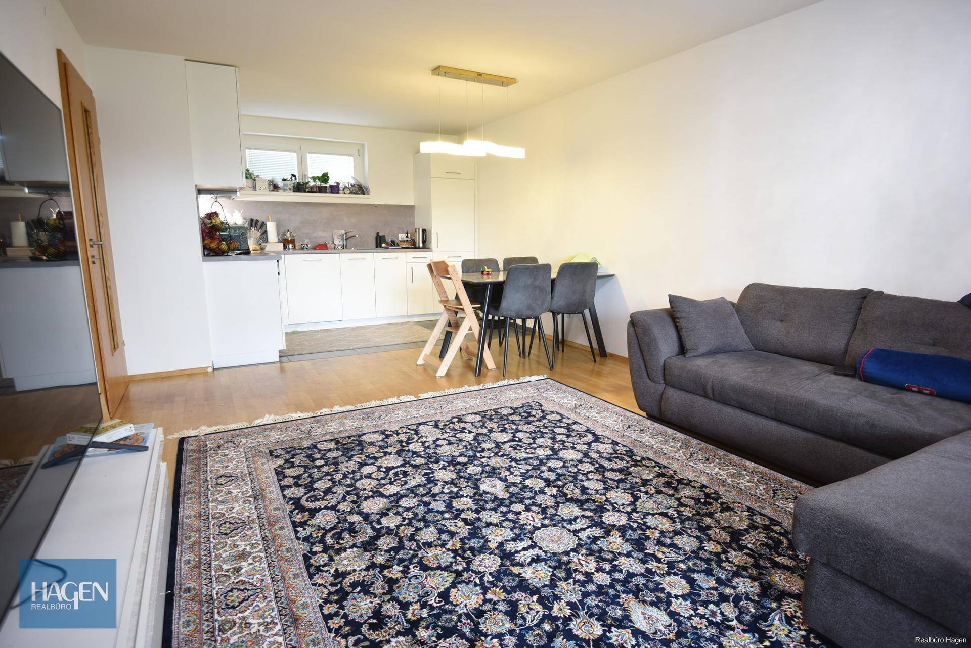 Offener Wohn- und Essbereich mit gemütlichem Sofa, Esstisch und integrierter Küche im Hintergrund.