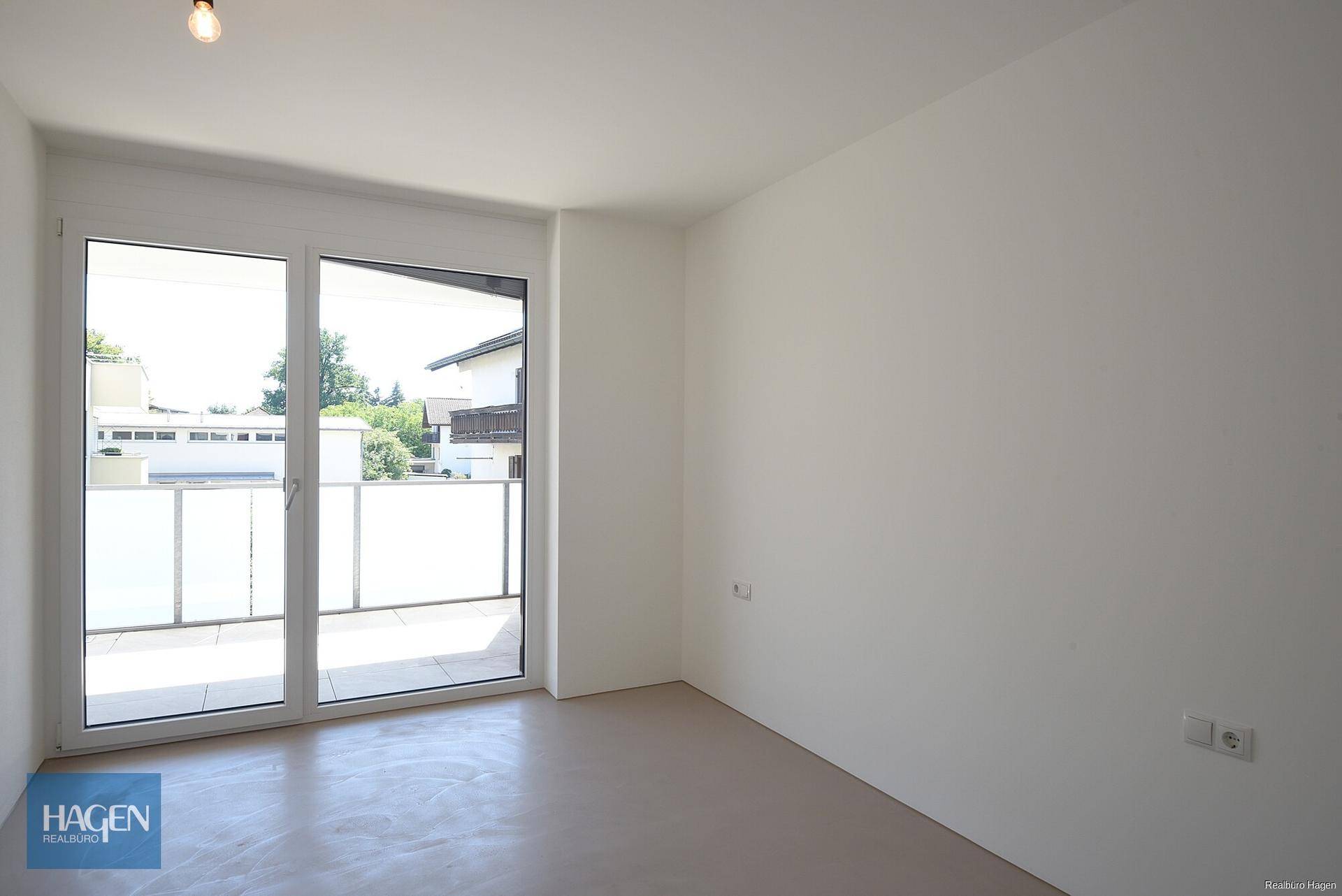 Helles Zimmer mit Zugang zu einem Balkon und großen Fenstern, bereit zur individuellen Gestaltung.