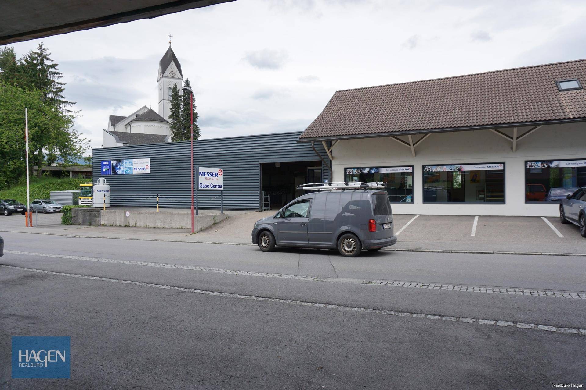 Seitenansicht des Gewerbegebäudes mit Ladebereich und angrenzendem Geschäftshaus.