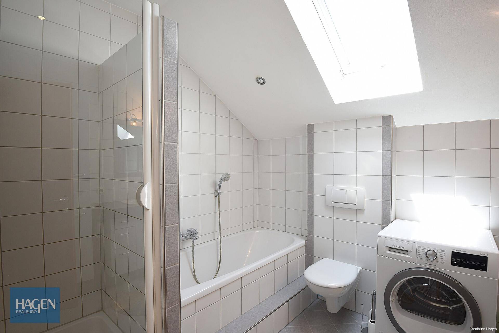 Helles Badezimmer mit Dusche, Badewanne, WC, Waschmaschine und Dachfenster.