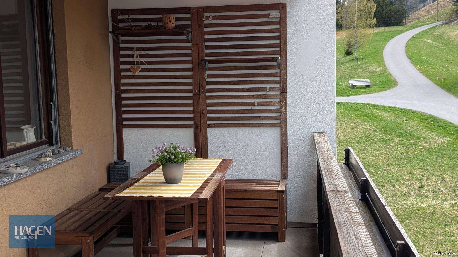 Gemütlicher Balkon mit Holztisch und Bänken, ideal für entspannte Stunden im Freien mit Aussicht.