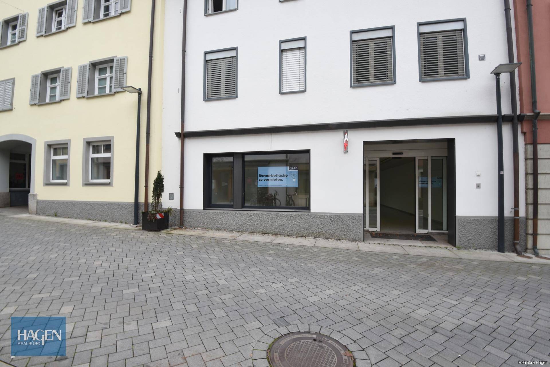 Nahaufnahme der Geschäftsfassade im Erdgeschoss mit großen Fenstern und automatischen Schiebetüren.