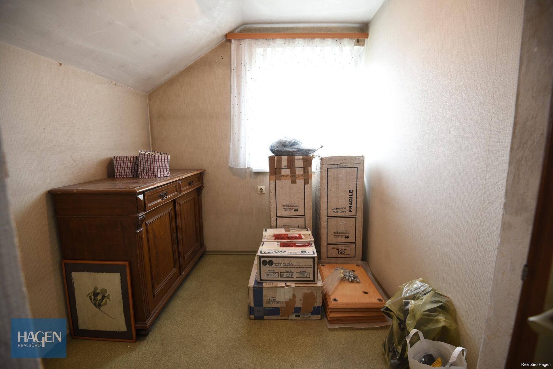 Kleiner Abstellraum im Dachgeschoss mit Fenster und Holzschrank.