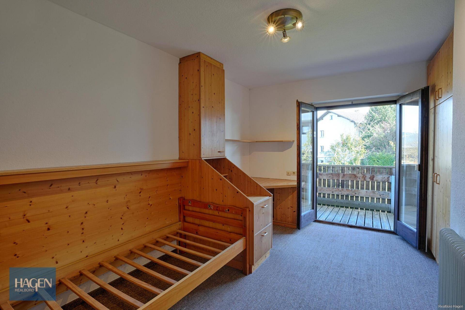 Schlafzimmer mit Holzeinbauten und Zugang zu einem kleinen Balkon.
