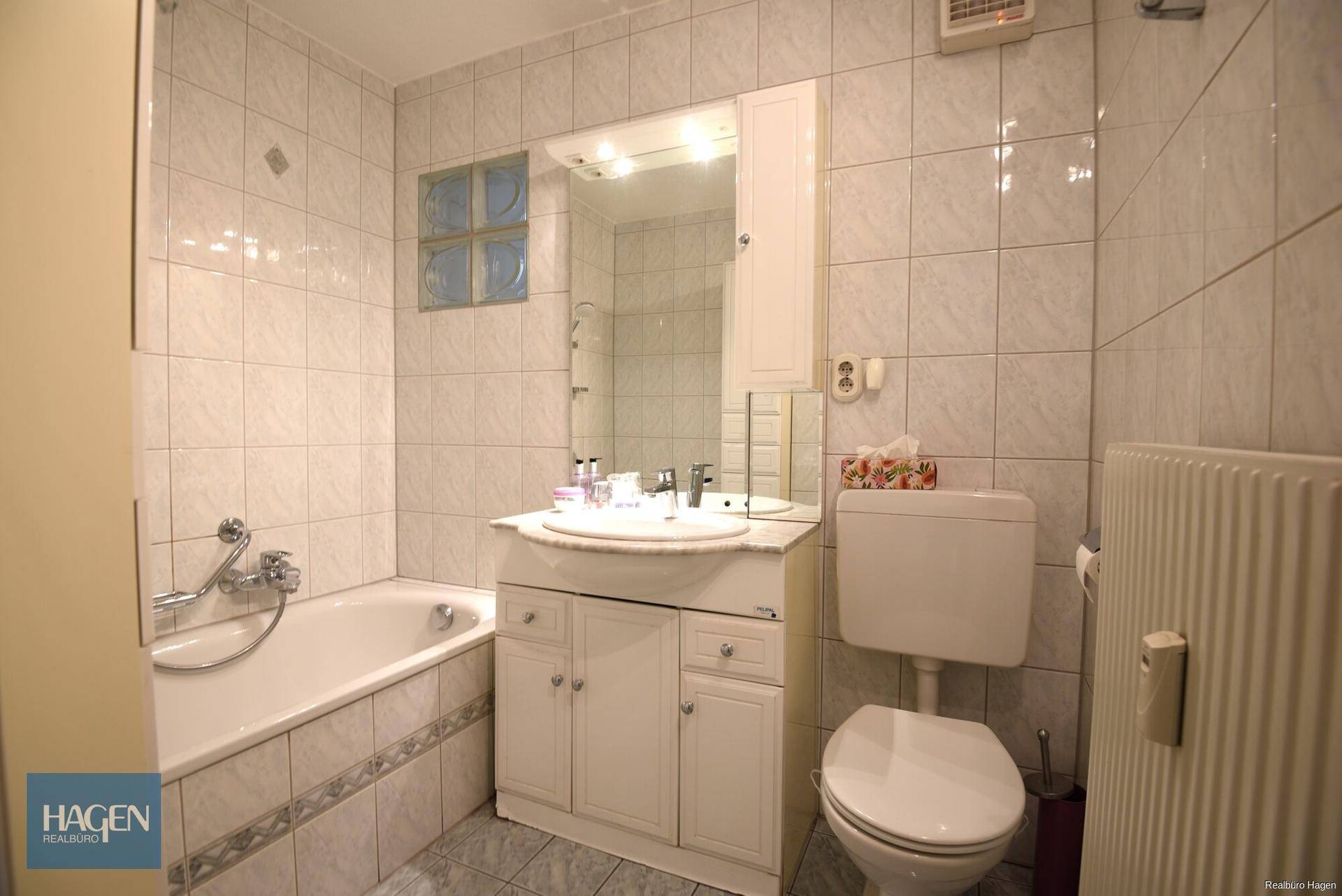 Gefliestes Badezimmer mit Badewanne, Waschbecken und Spiegelschrank.