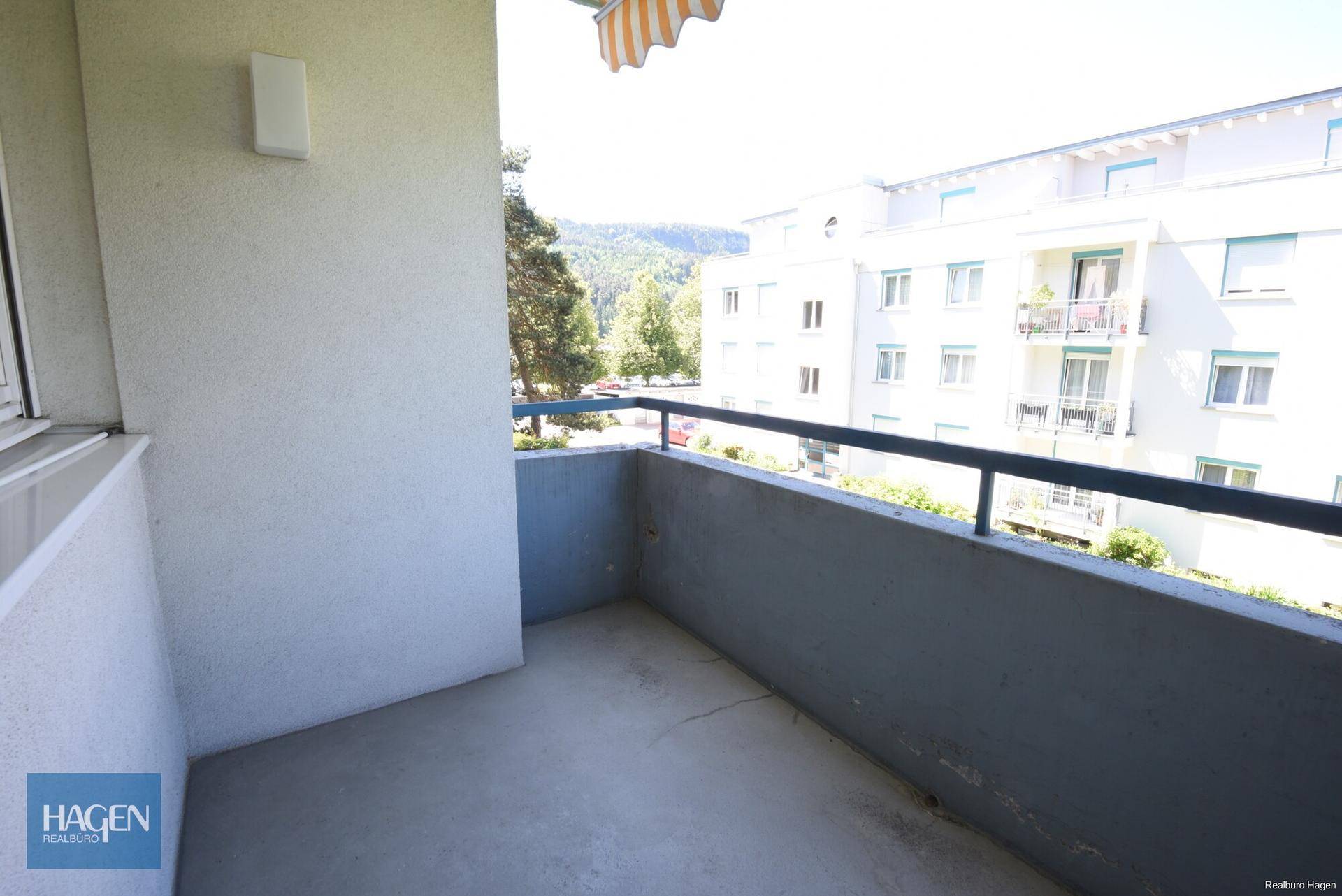 Balkon mit Blick auf die Umgebung und eine Markise für Sonnenschutz.
