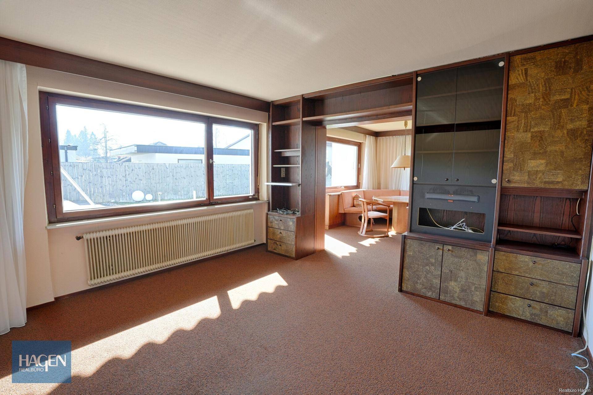 Geräumiges Wohnzimmer mit Teppichboden, großen Fenstern und Einbauschränken.