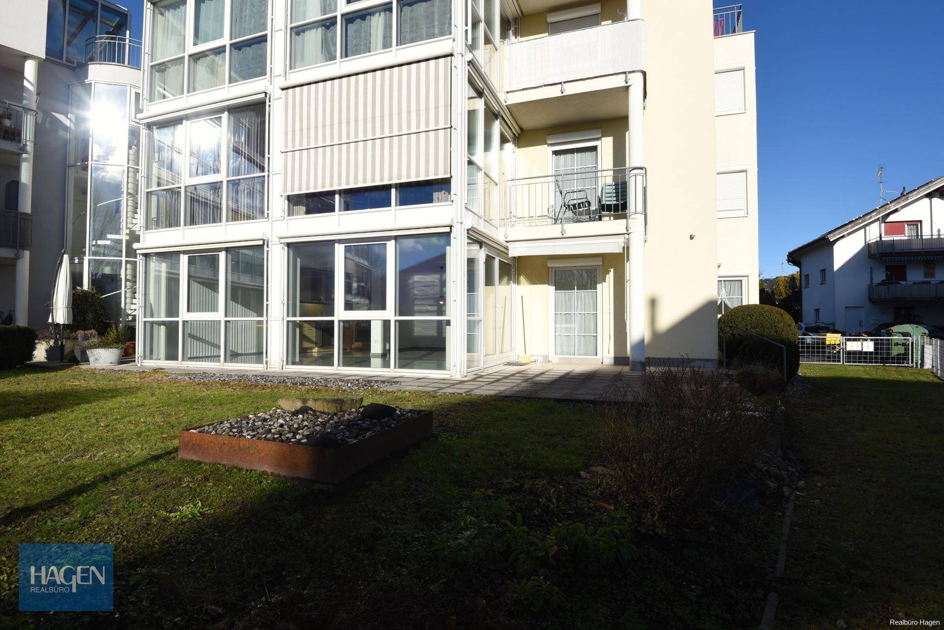 Gepflegter Gartenbereich mit Rasenfläche und Terrasse vor dem modernen Wohngebäude.