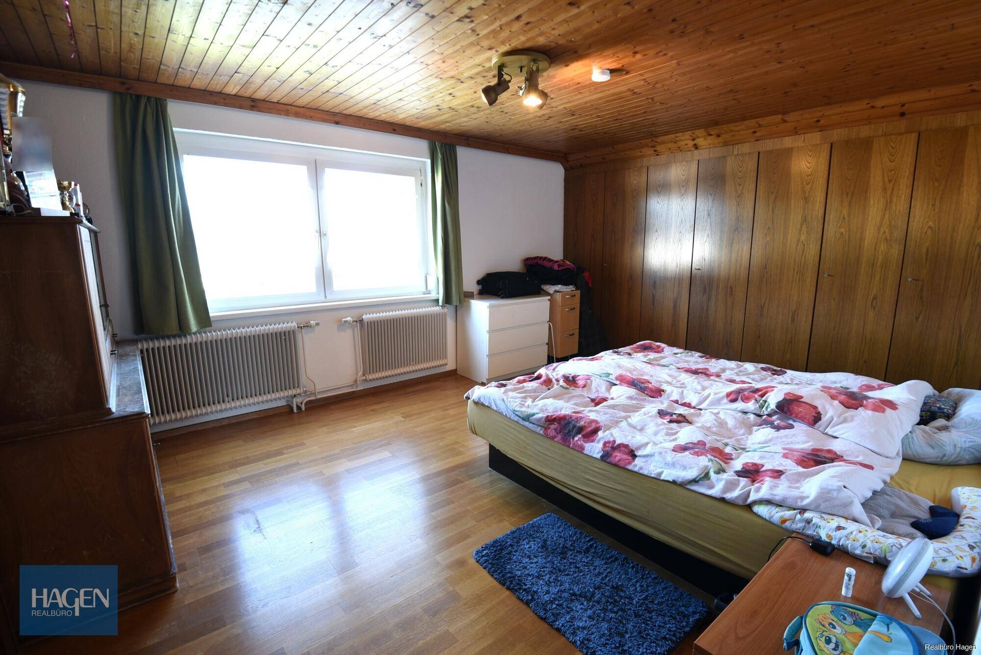 Geräumiges Schlafzimmer mit Holztäfelung, Parkettboden und großem Fenster.