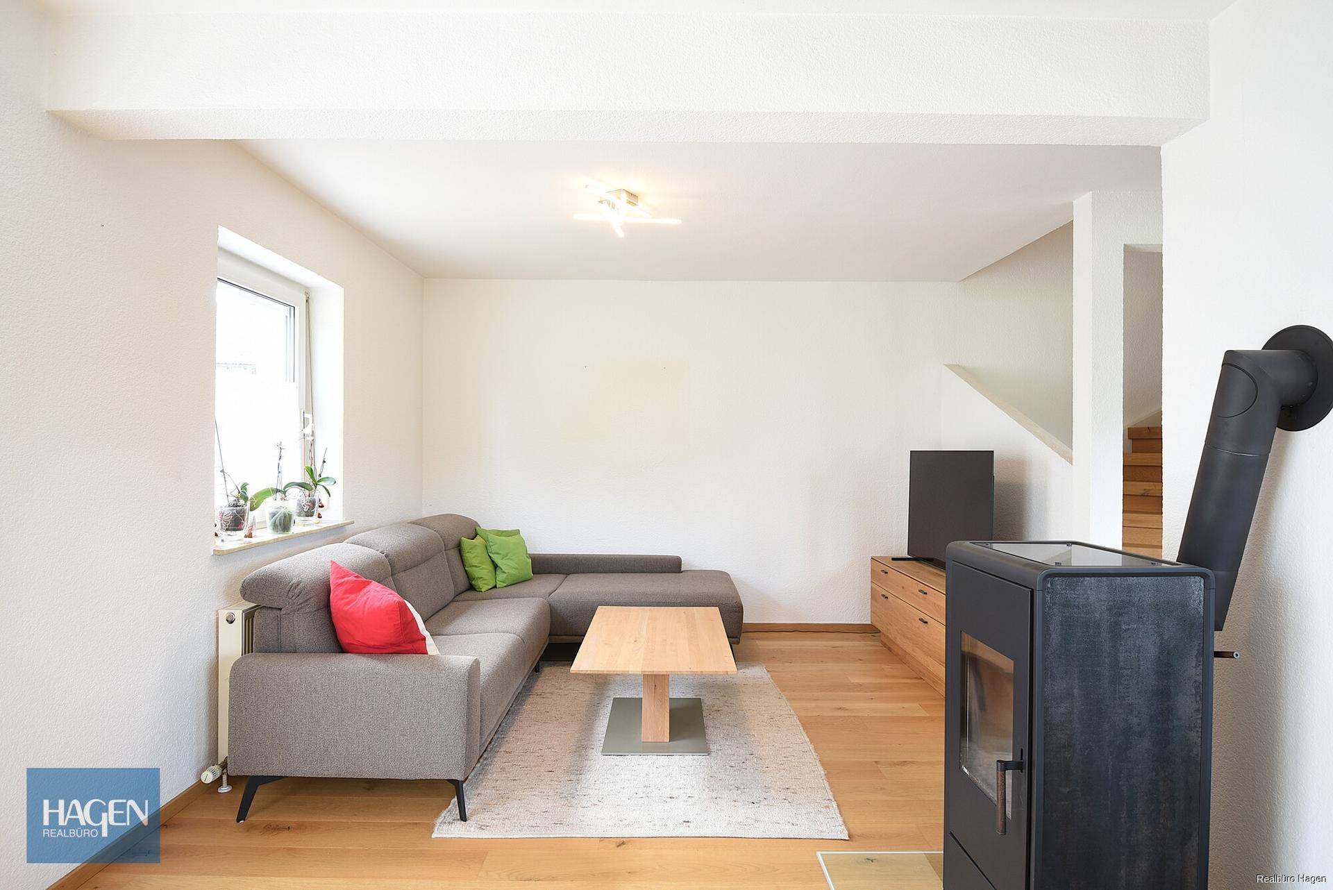 Gemütliches Wohnzimmer mit Ecksofa, Holzboden und Kaminofen für entspannte Abende.