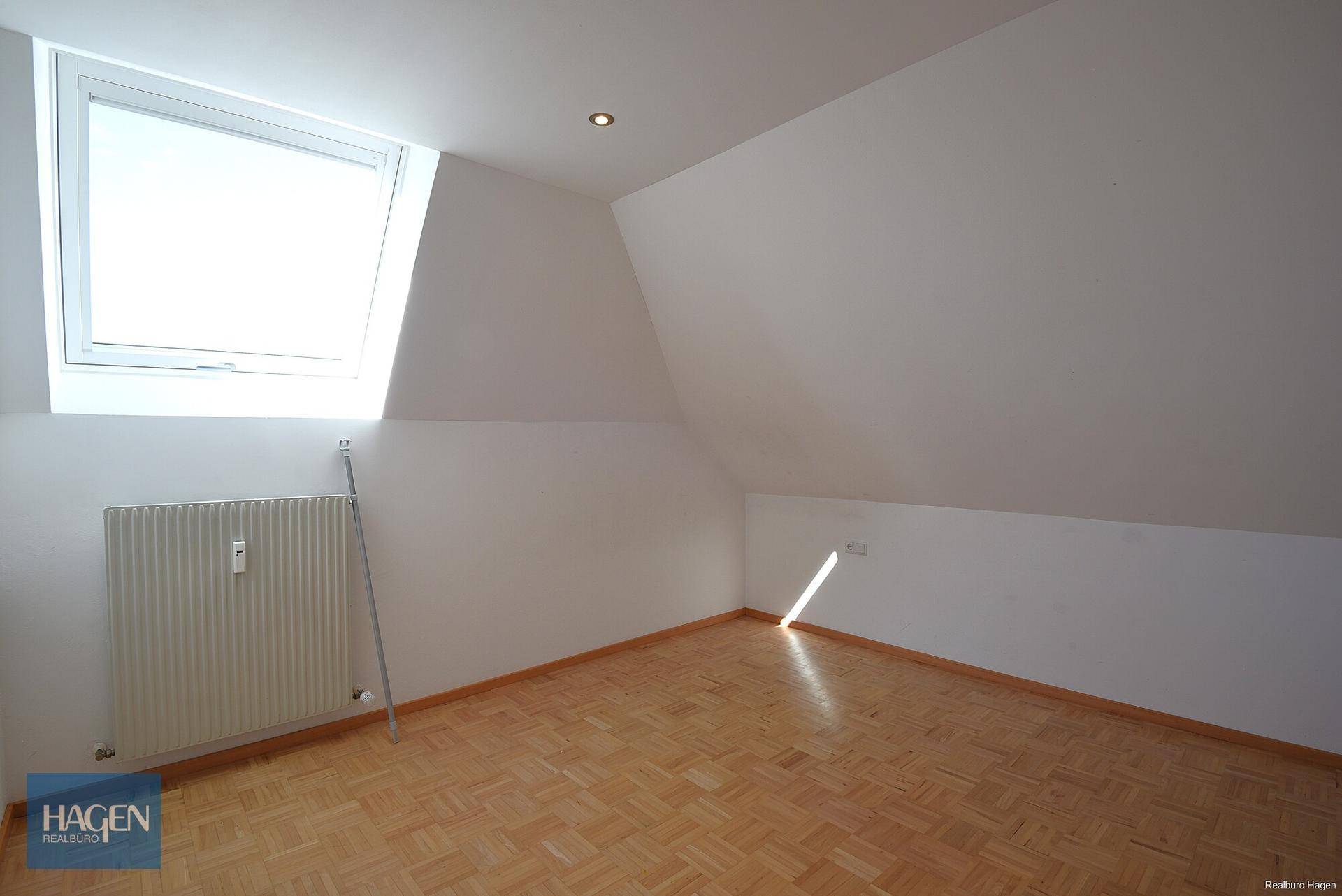 Lichtdurchflutetes Schlafzimmer im Dachgeschoss mit Parkettboden und Dachfenster.