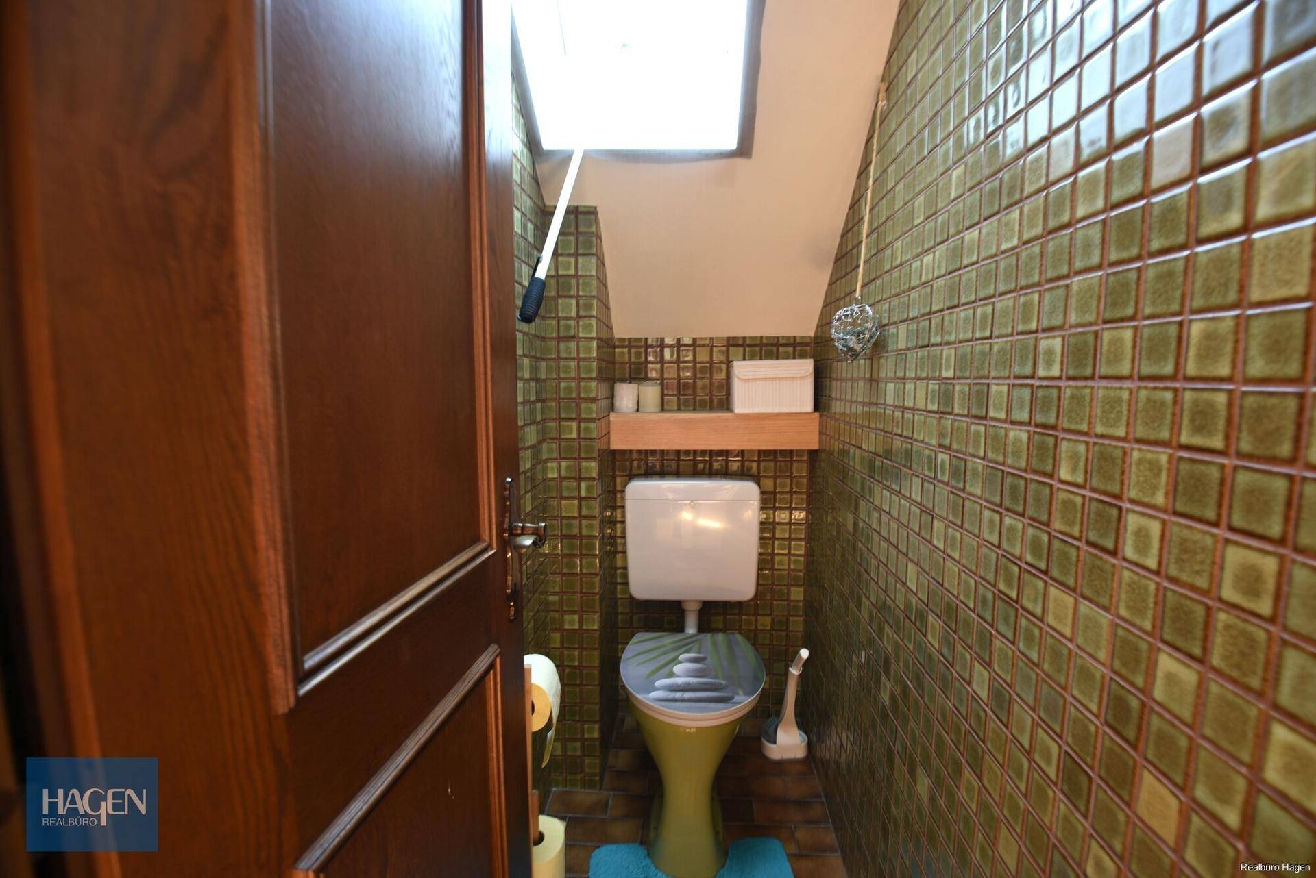 Kleines Gäste-WC mit grünen Fliesen und WC im Retro-Stil.