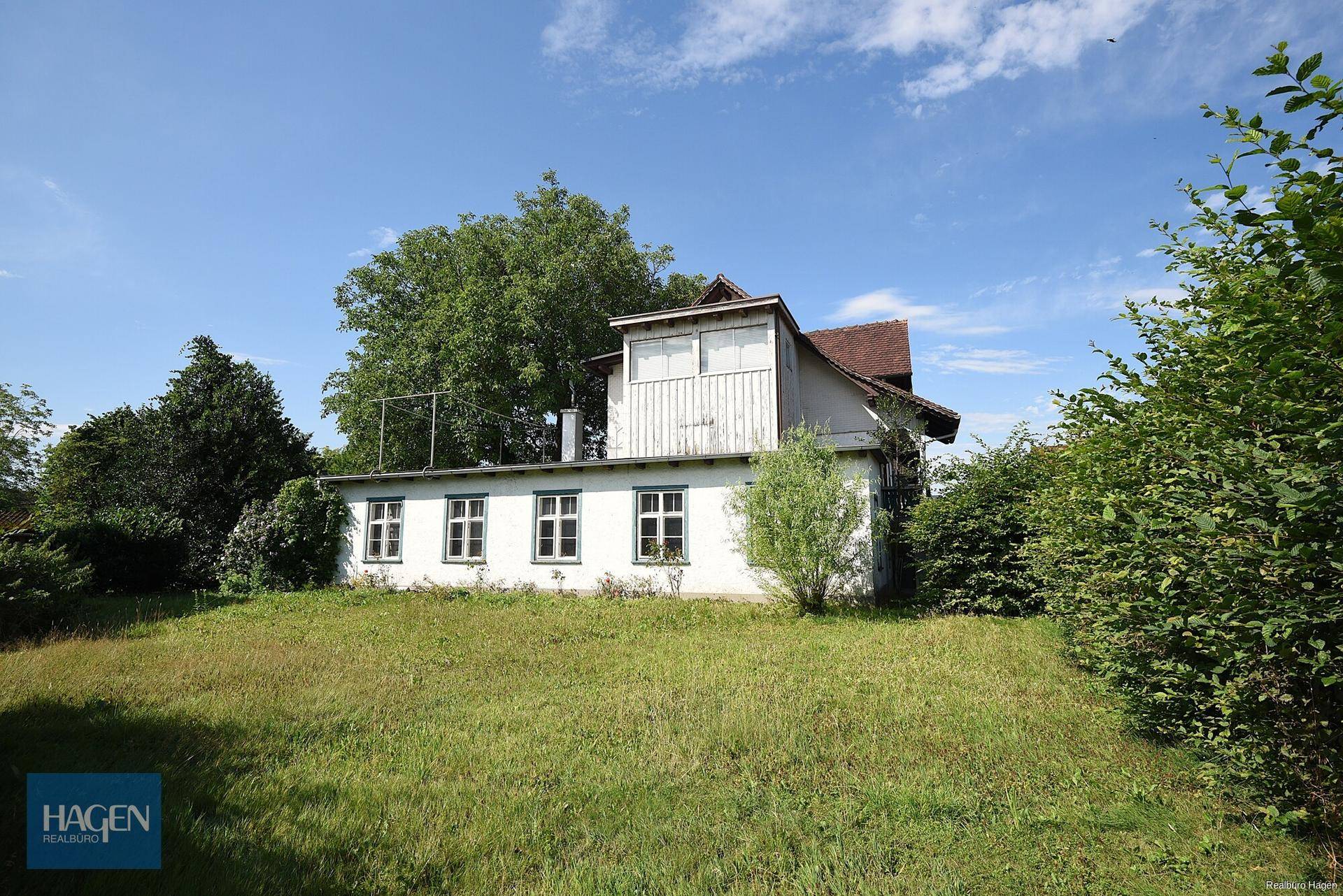 Seitenansicht des Hauses mit Anbau und großem Gartenbereich unter blauem Himmel.