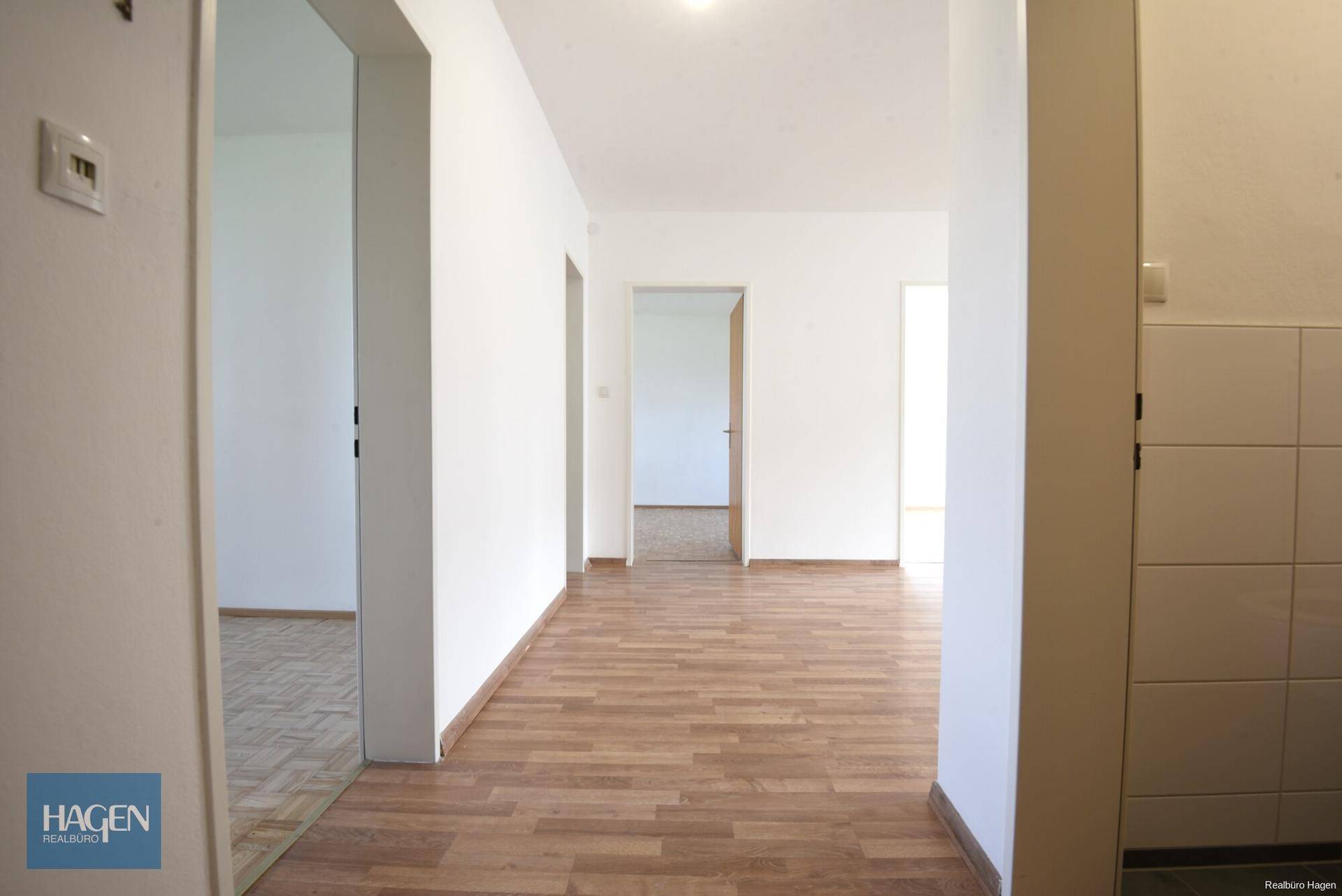 Langer Flur mit hellem Parkettboden, der zu verschiedenen Räumen der Wohnung führt.