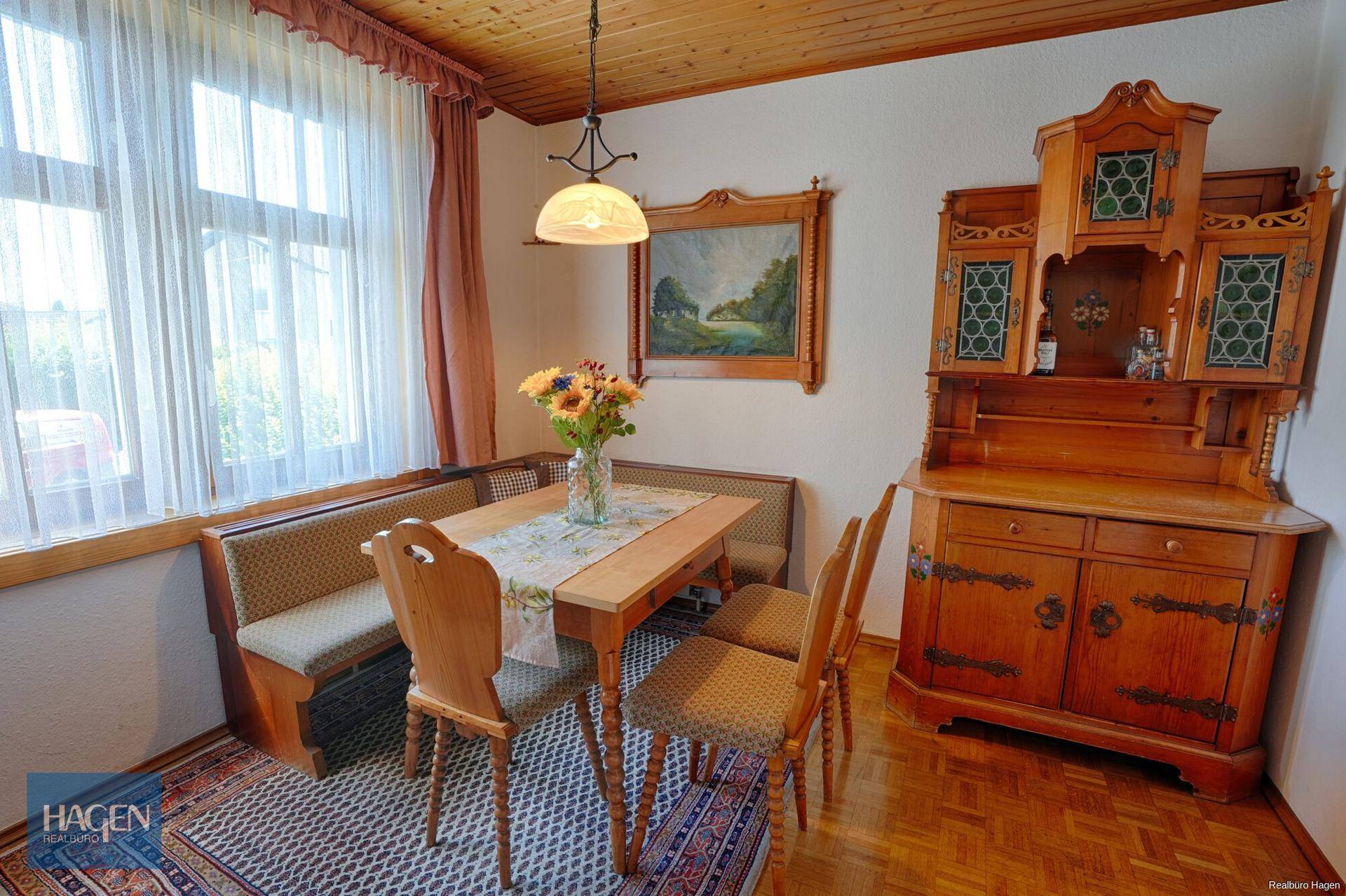 Essbereich mit traditionellen Holzmöbeln, Eckbank und Parkettboden unter einer Holzdecke.