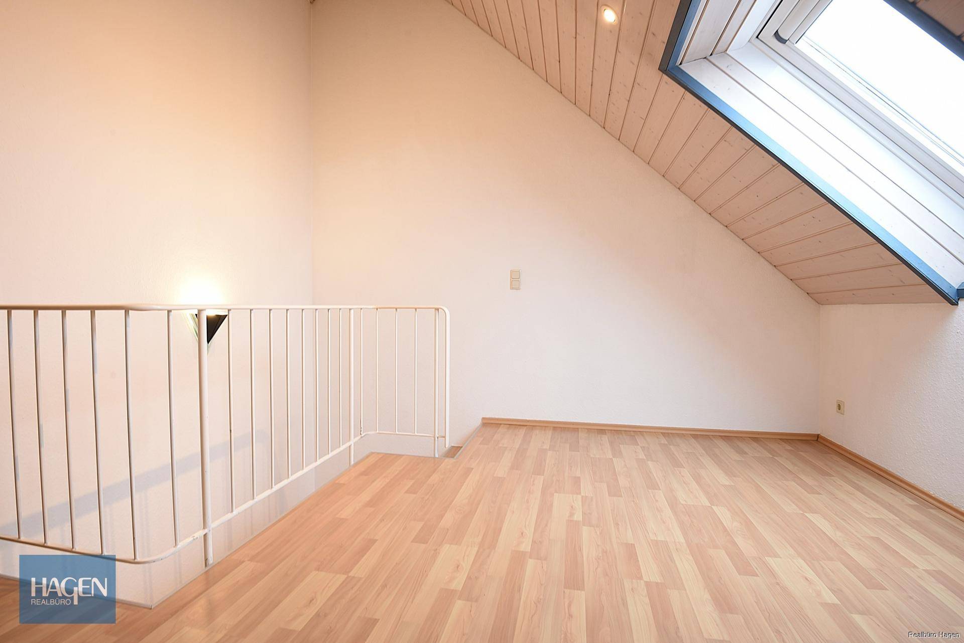 Heller Dachbodenraum mit Dachschräge, Holzverkleidung und Laminatboden.