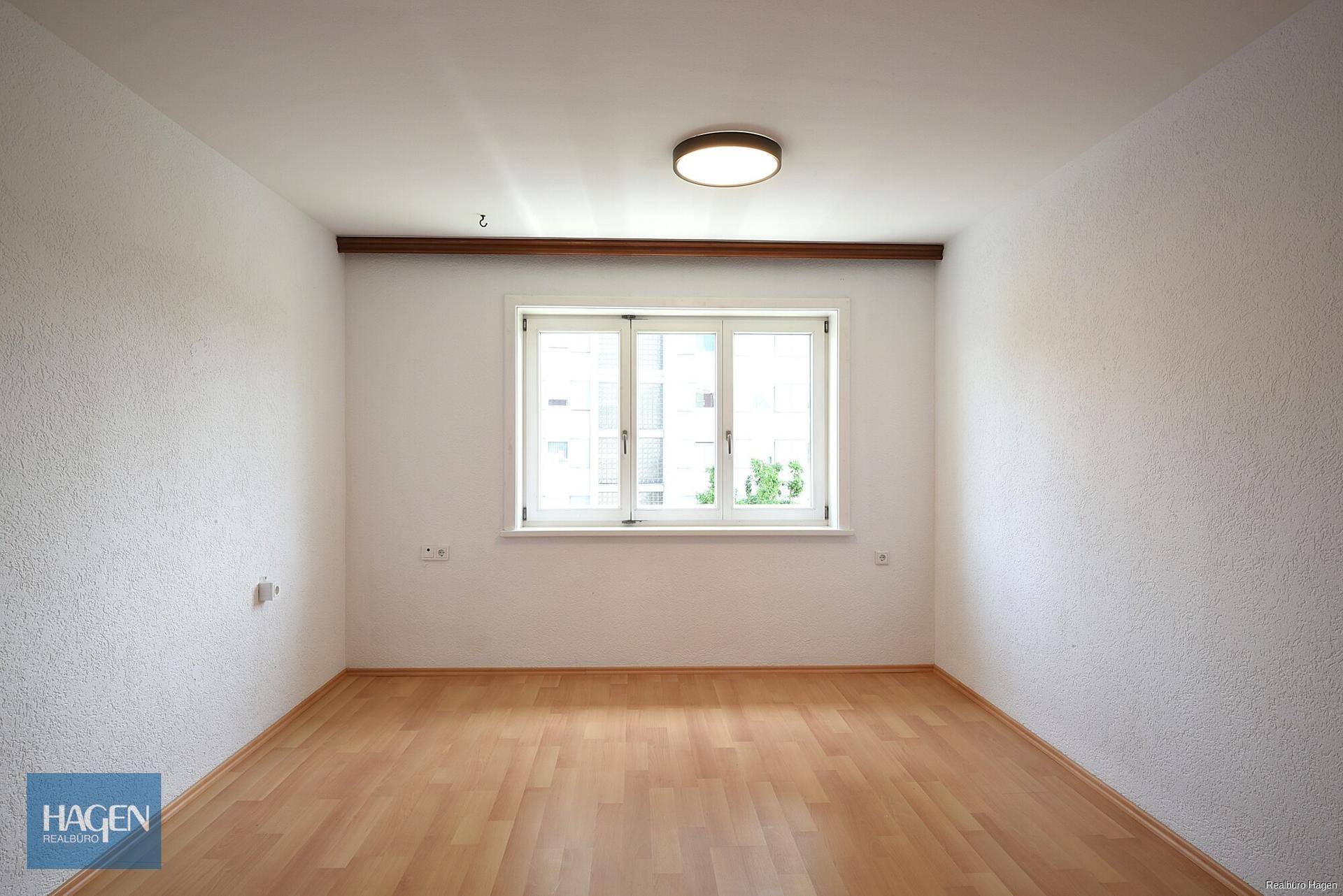 Helles Zimmer mit Laminatboden und einem großen Fenster, ideal als Schlafzimmer oder Büro nutzbar.