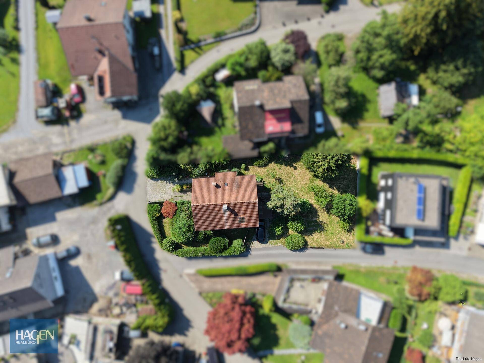 Vogelperspektive eines Wohnhauses mit Garten, Zufahrt und der umliegenden Siedlung.