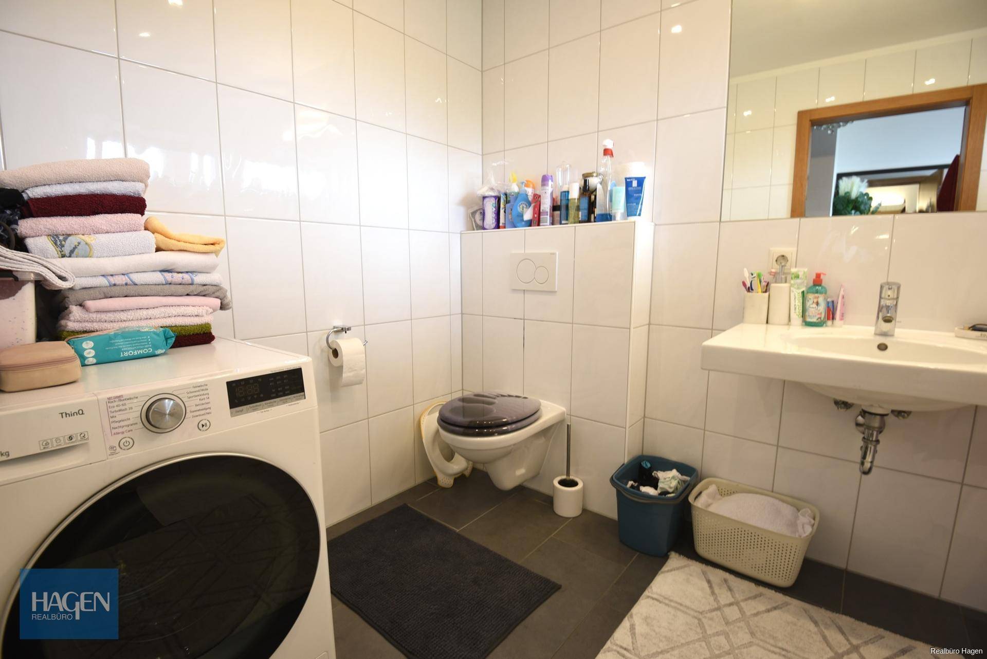Funktionales Badezimmer mit Waschmaschine, Toilette und Waschbecken, praktisch eingerichtet.